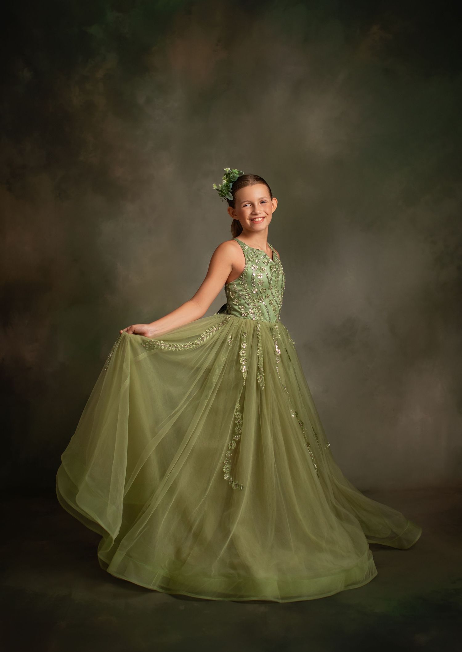 Elegant olive green ballgown with layered tulle skirt in dreamy studio portrait setting.
