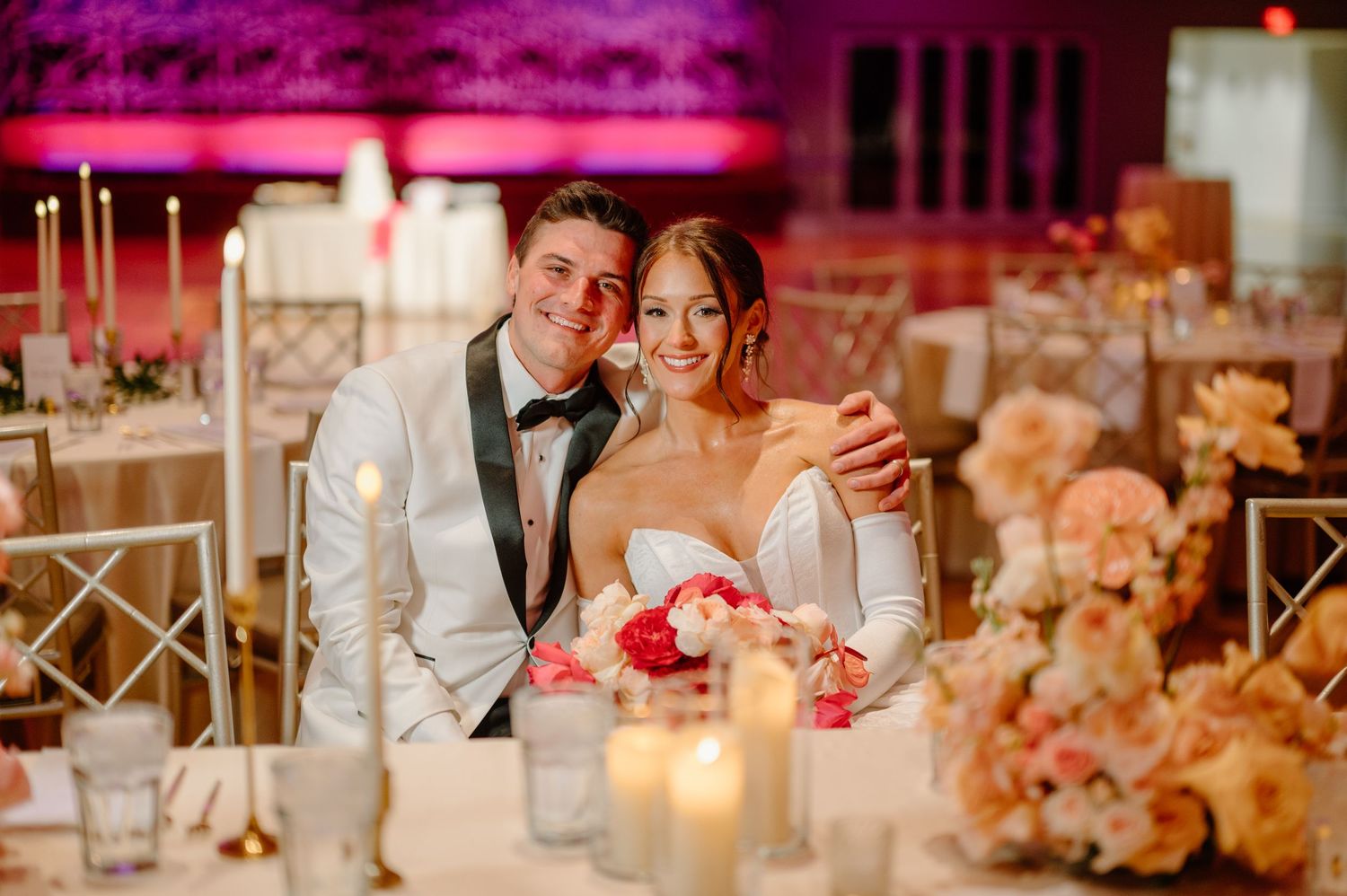 Wedding couple poses in front of a grand pink colonial style mansion with white columns.