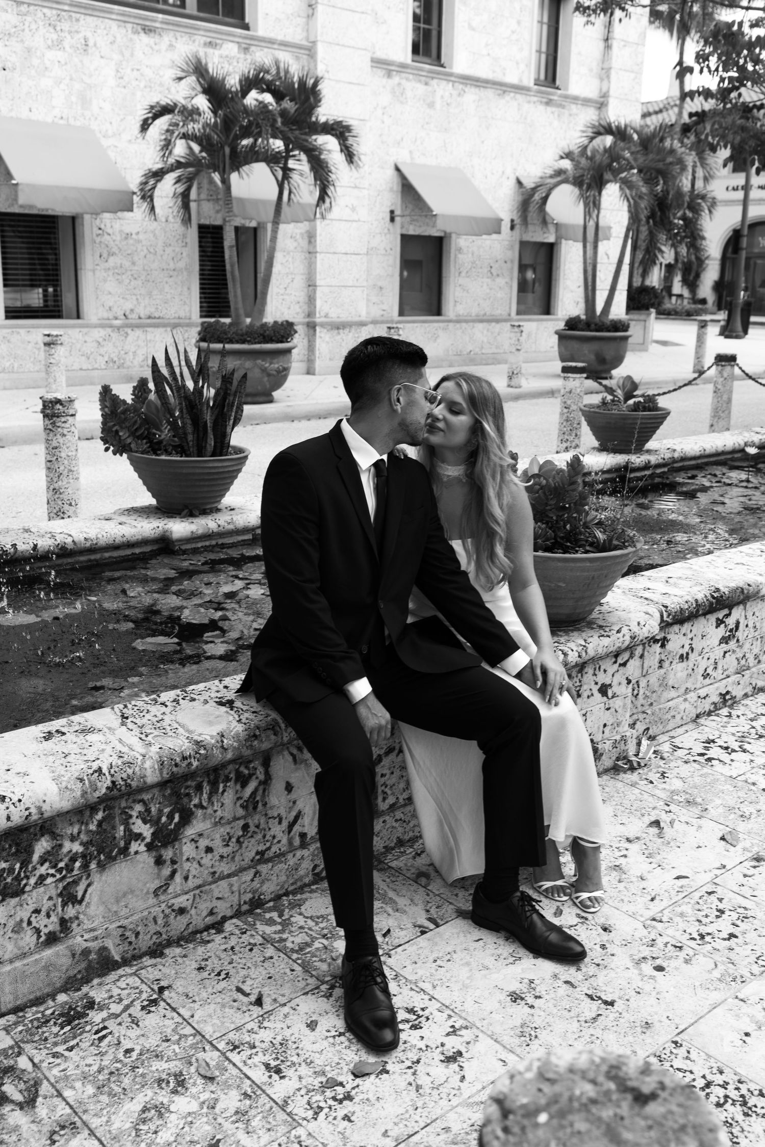 A romantic couple sitting with pampas grass and picnic basket in a rustic countryside setting.