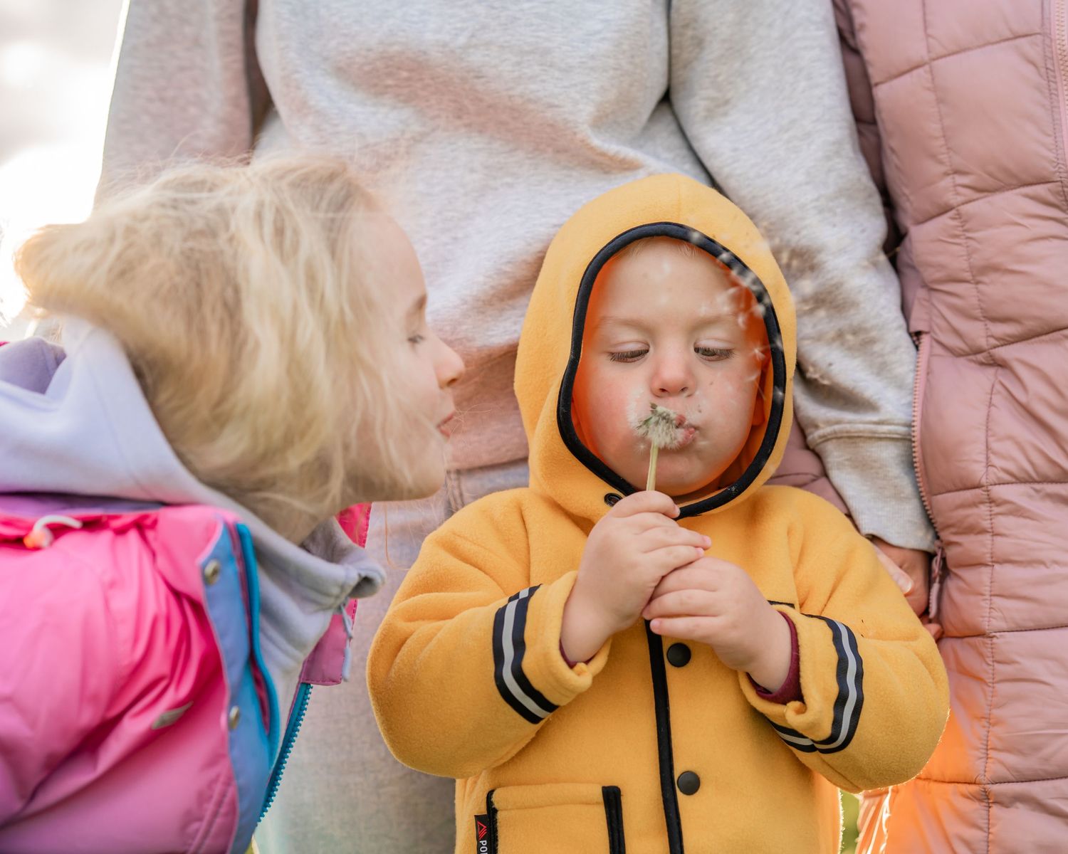 Two children in winter coats share a heartwarming moment while enjoying outdoor activities.