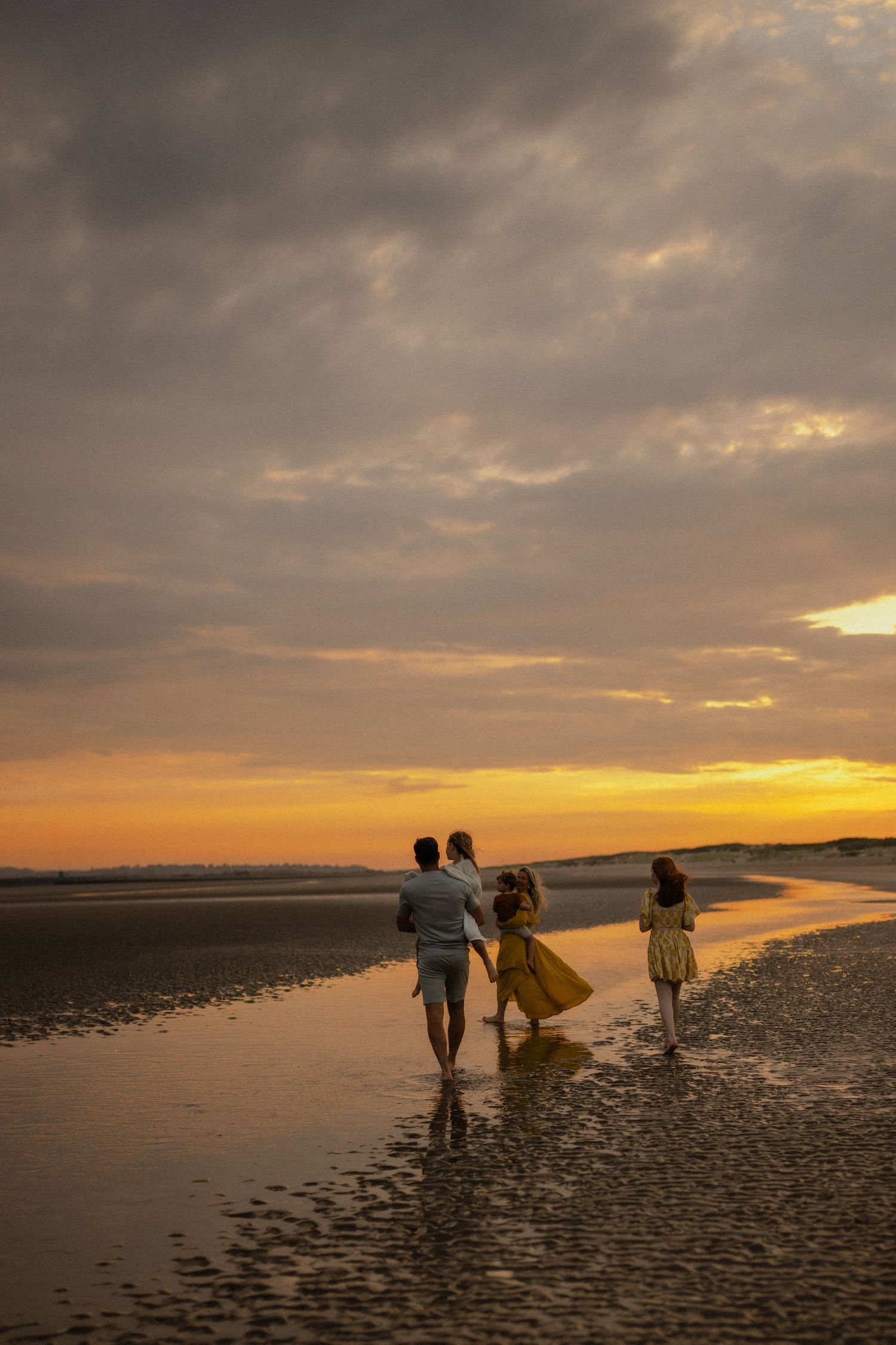 A family walking on the beach at sunset during a photo session with Forever Ours Photography in Camber Sands, Kent, UK