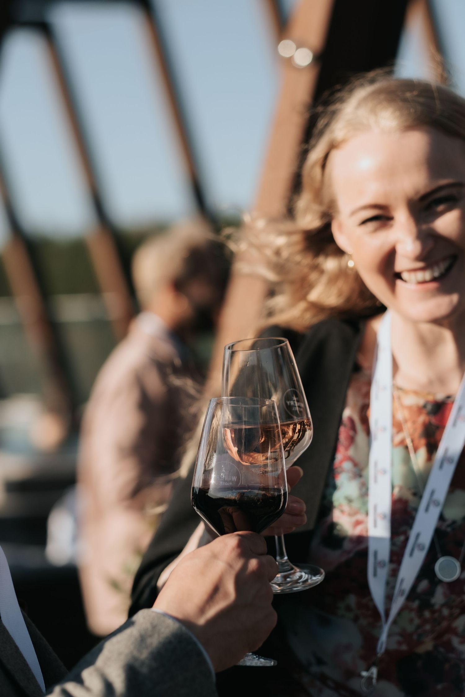 woman laughs and cheers with her wine glass to another while being captured by business photographer in Stockholm