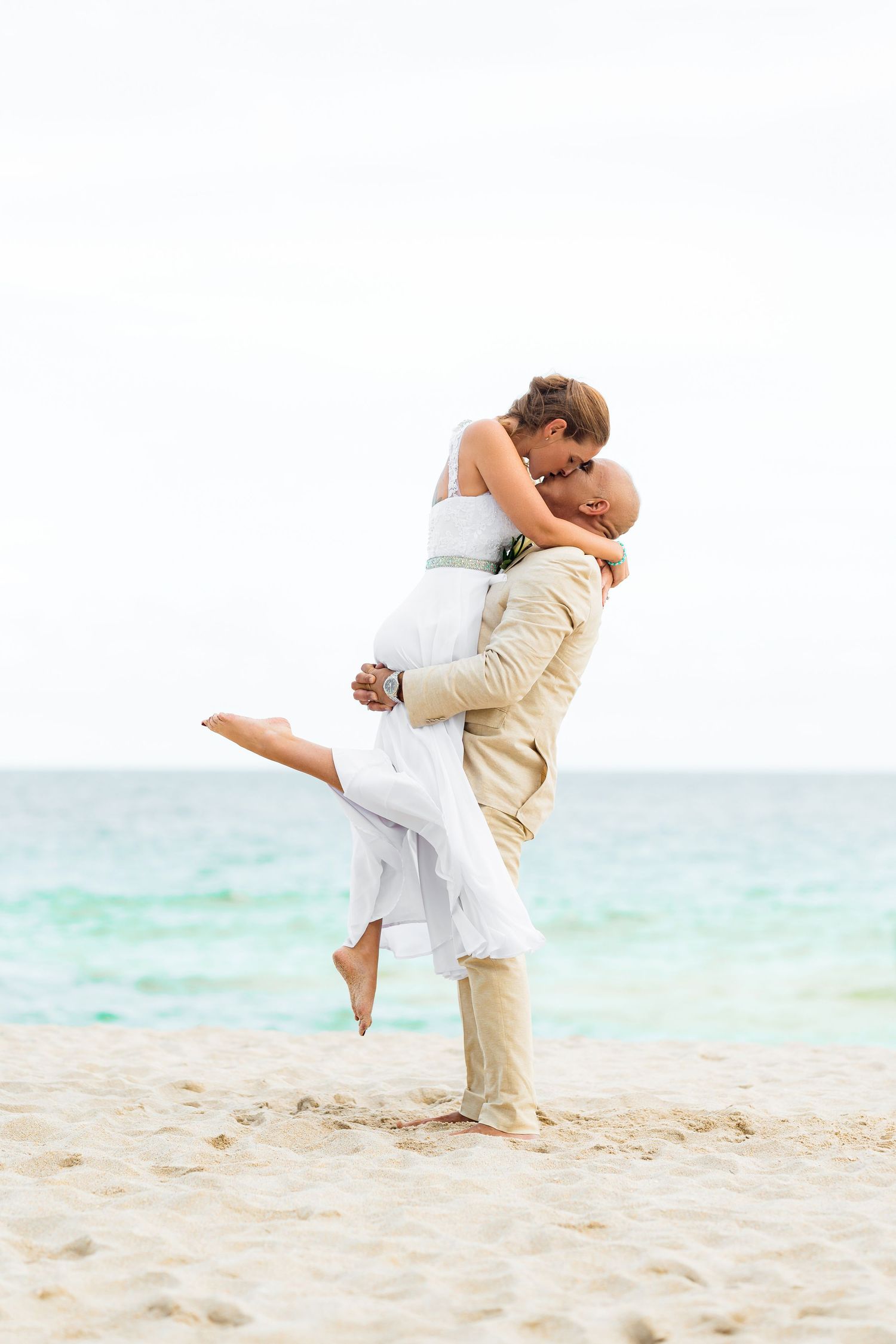 A romantic beach embrace with waves in the background as a couple celebrates their love.