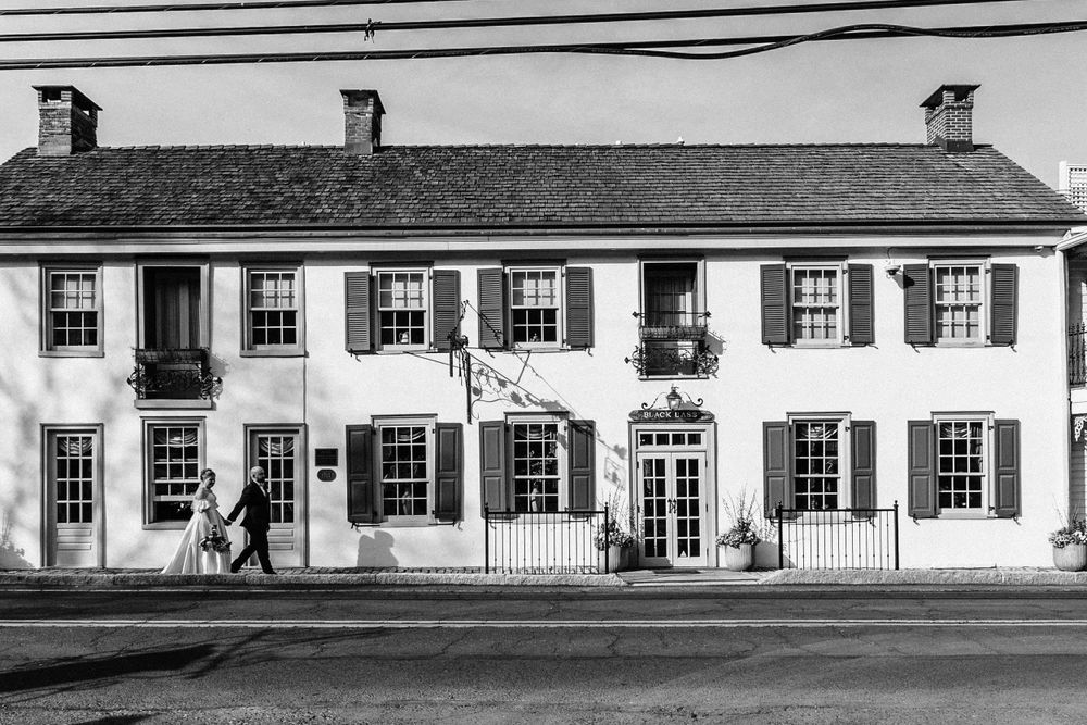 A classic black and white photo of a historic colonial-style building with shuttered windows and brick facade.