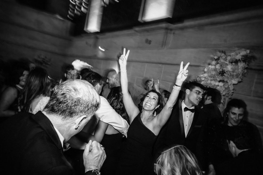 Black and white photo of partygoers celebrating on a dance floor with raised arms and joyful expressions.
