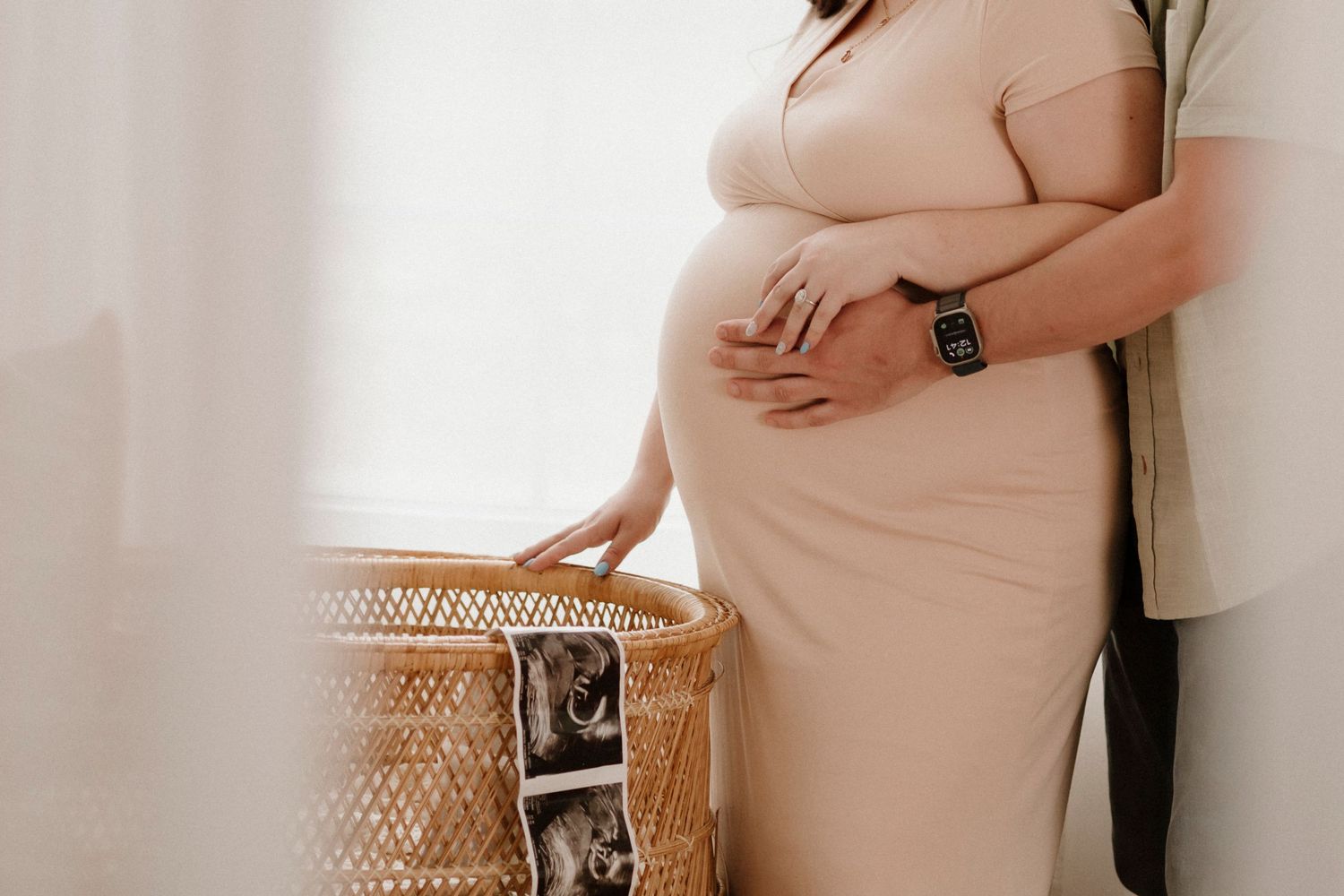Side view of maternity moment with woven chair and window light.