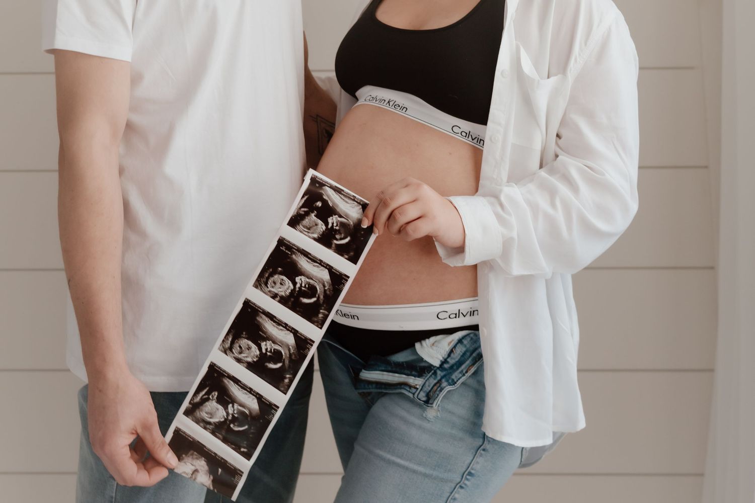 Close-up of couple holding ultrasound strip photos during pregnancy photoshoot.