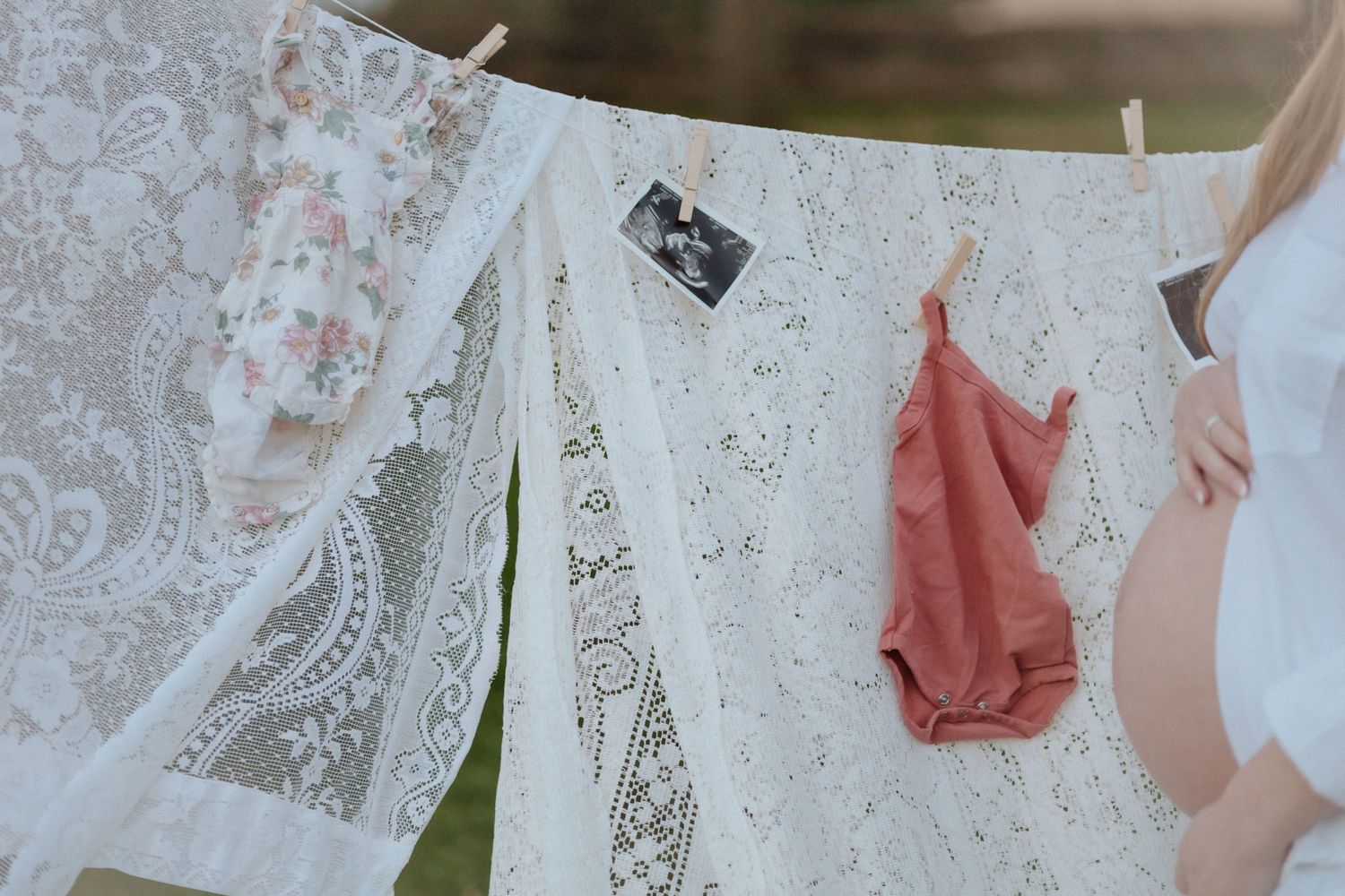 Vintage lace and clothing hanging on clothesline with ultrasound photo clipped between items.