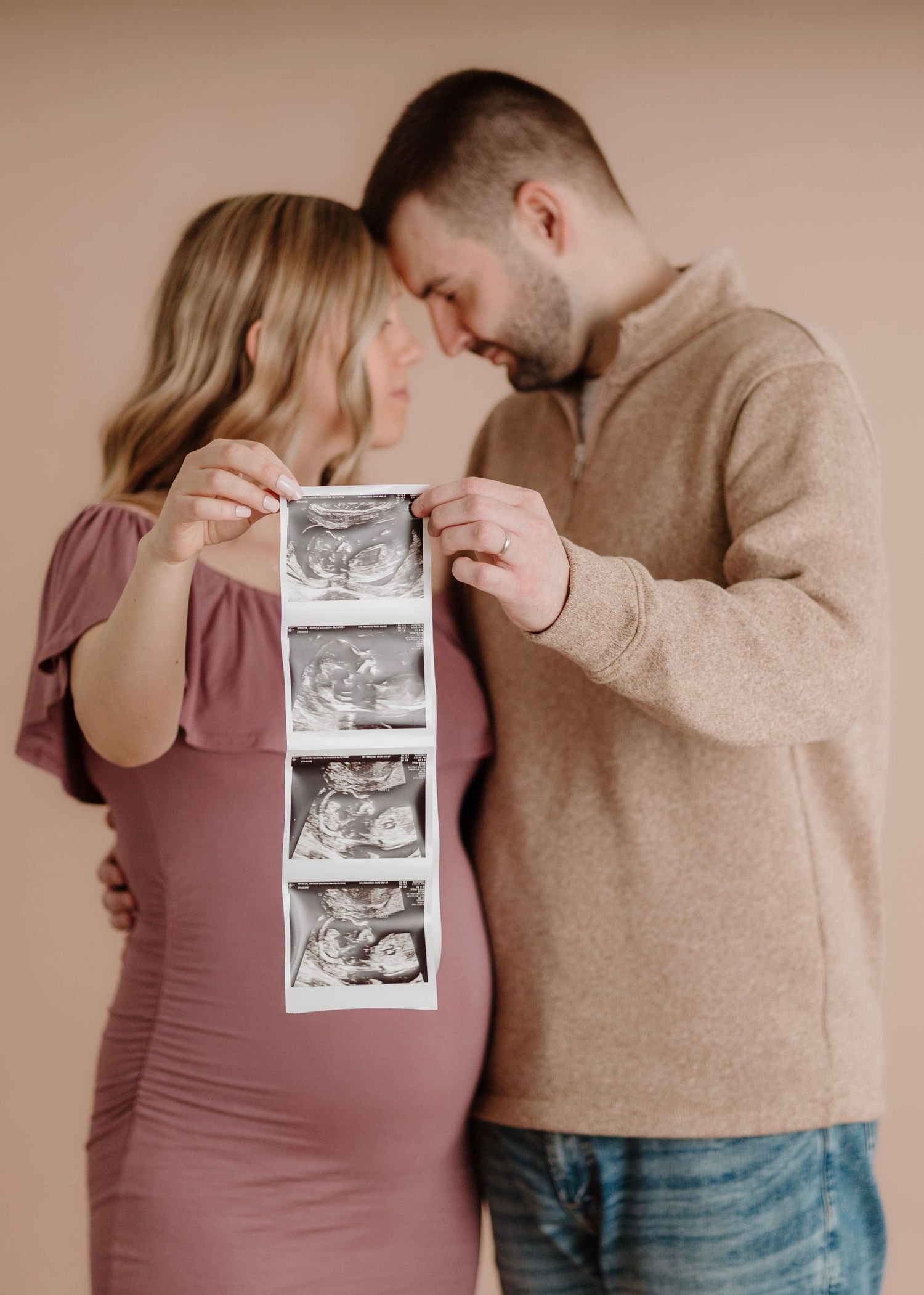 A couple sharing a special moment while holding ultrasound photos.