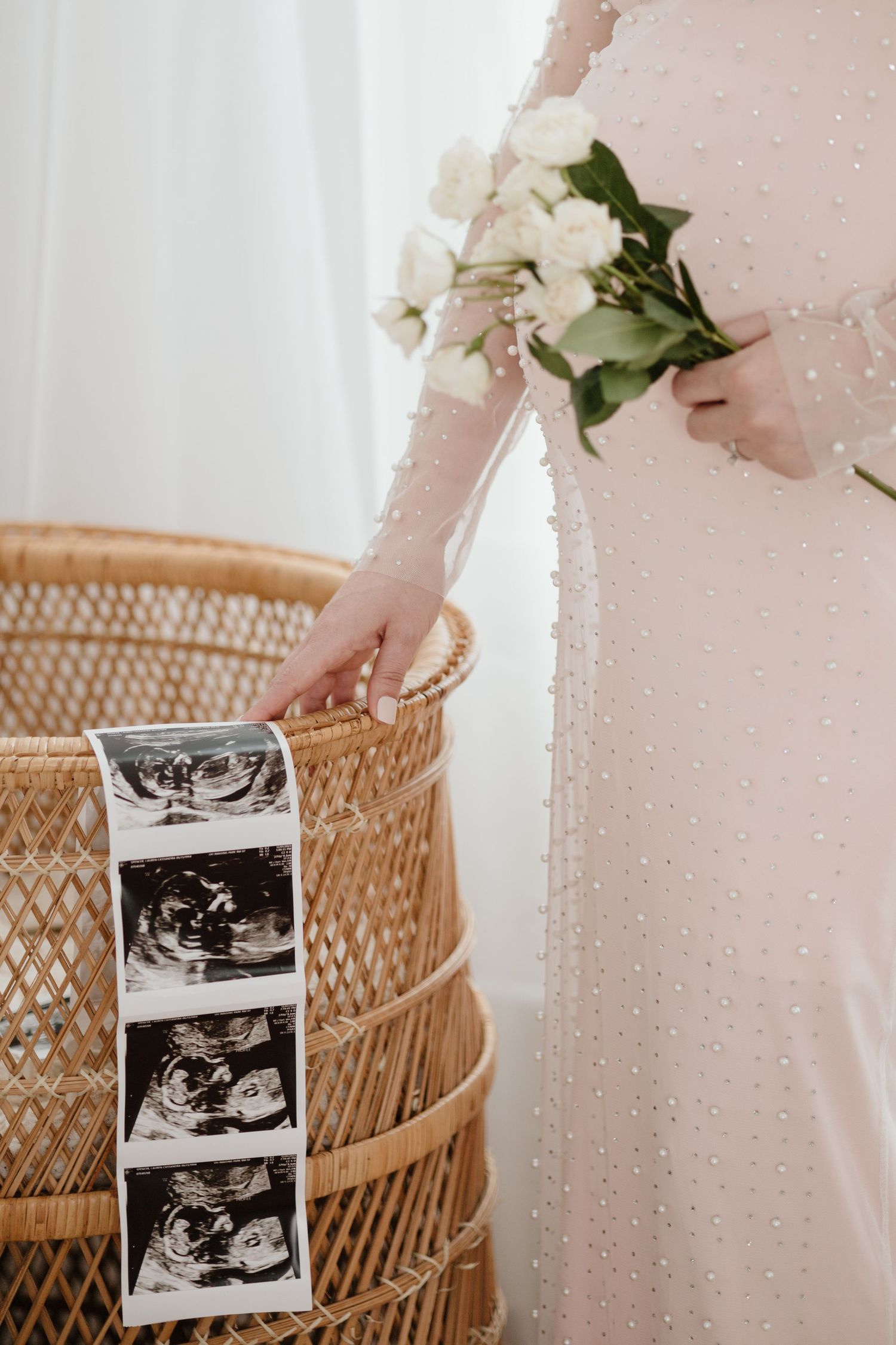 Ultrasound photos displayed beside a pink pearl dress and white flowers.