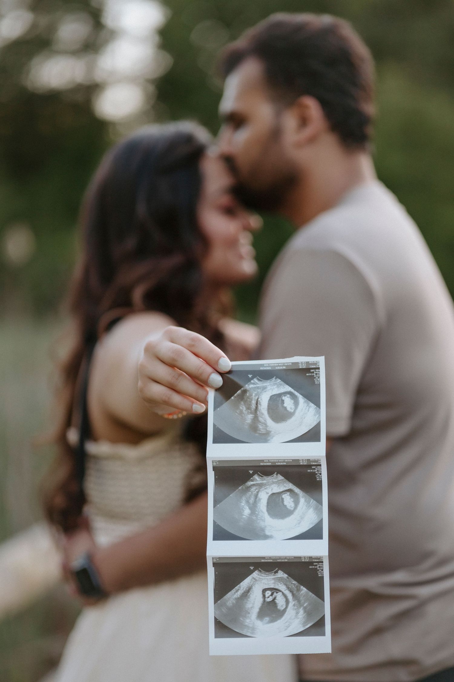 A couple holding ultrasound photos during a pregnancy announcement photoshoot.
