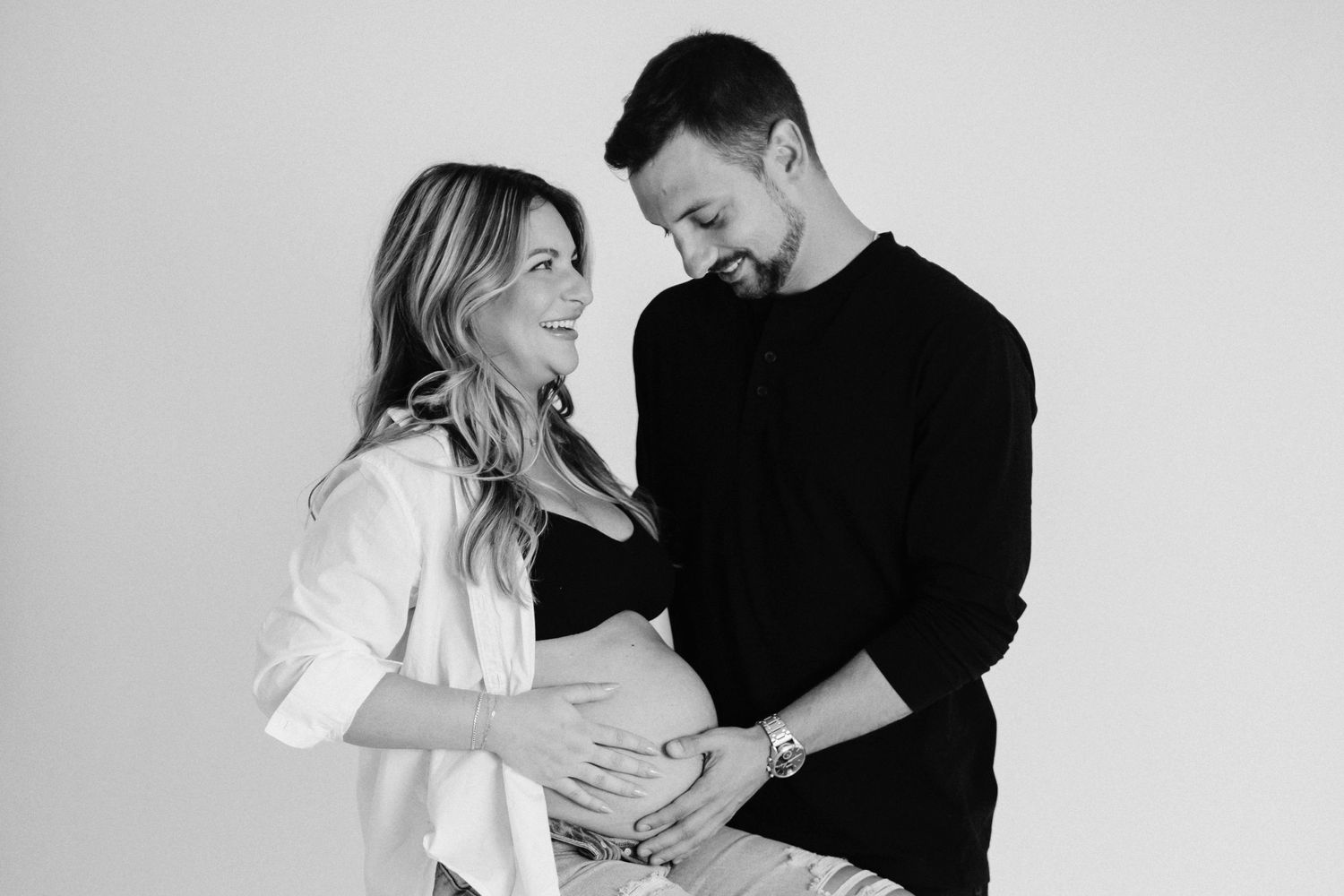 Black and white maternity photo capturing tender moment between expecting couple.