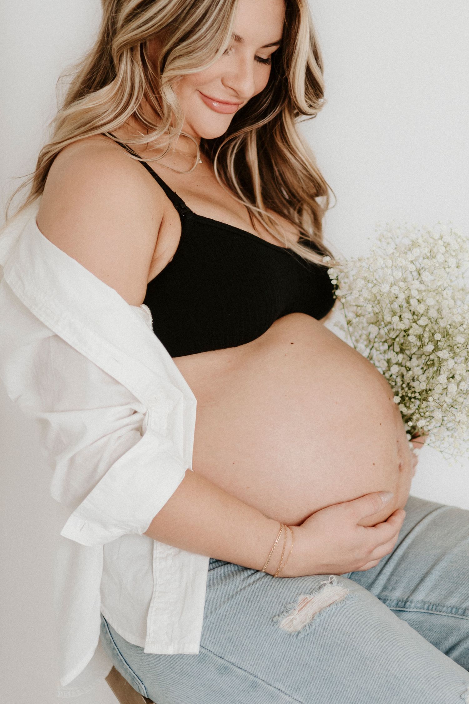Maternity photo with baby's breath flowers and white shirt.