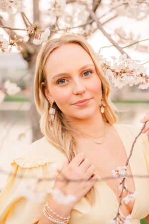 A senior girl in a yellow dress in the midst of cherry blossom branches in Huntsville Alabama