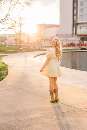 A pulled back shot of a beautiful female senior during golden hour at Big Spring Park in Huntsville Alabama