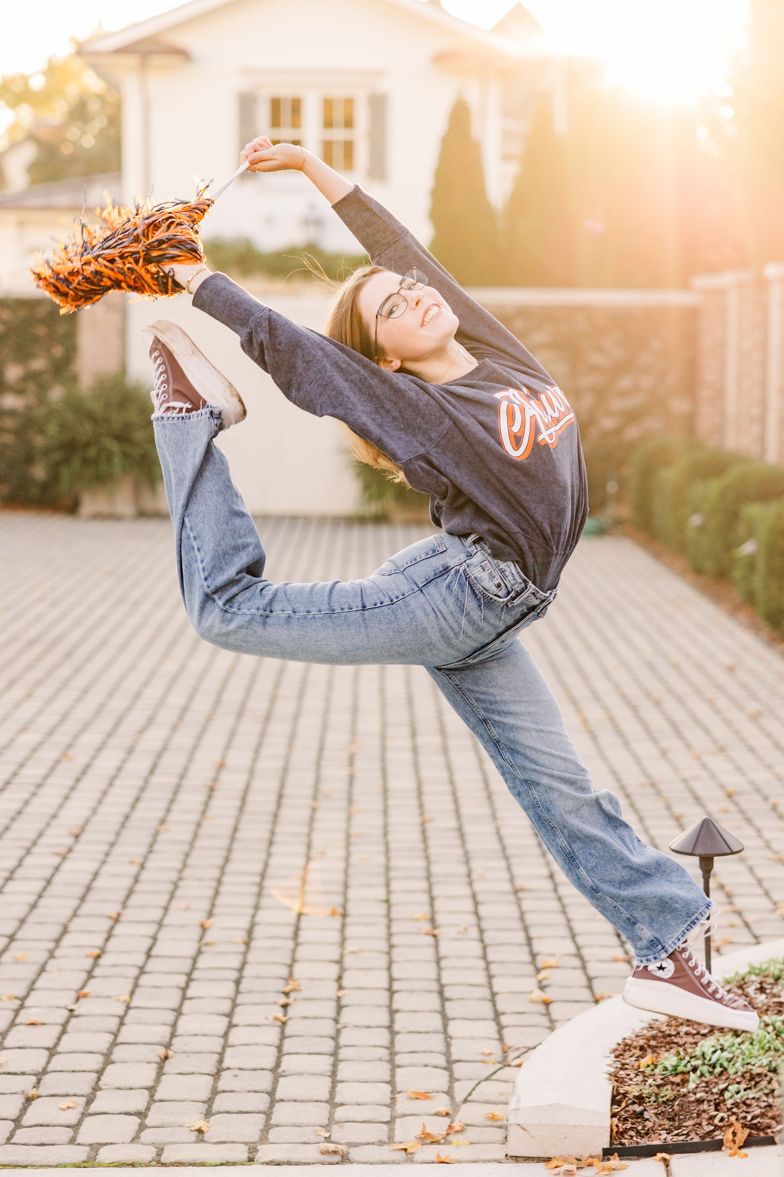 Woman performing acrobatic pose with dried flowers at sunset.