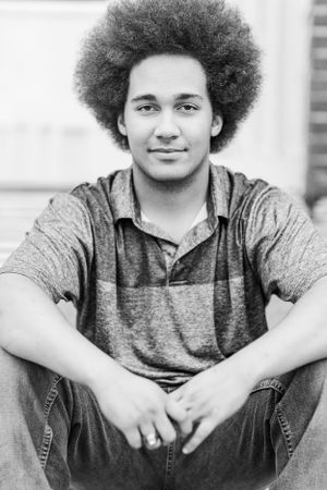 Black and white portrait of someone with an afro hairstyle wearing casual attire.