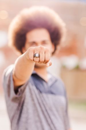 Close-up of a hand displaying a ring while wearing a grey shirt.