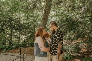 A romantic couple shares an intimate moment together in a wooded forest setting.