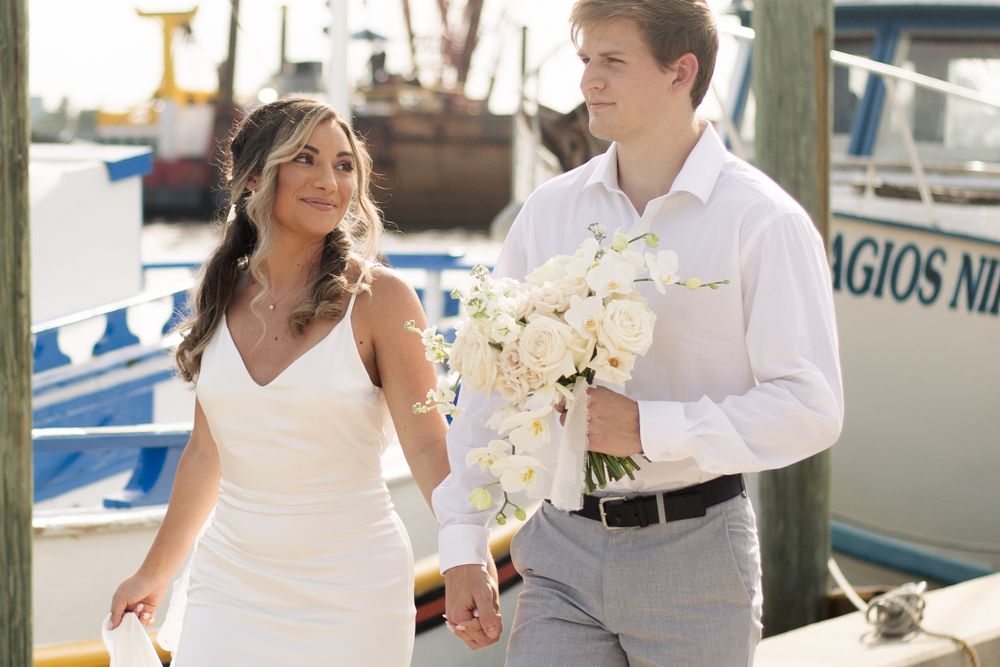 A couple shares a joyful moment while walking past boats at a marina.