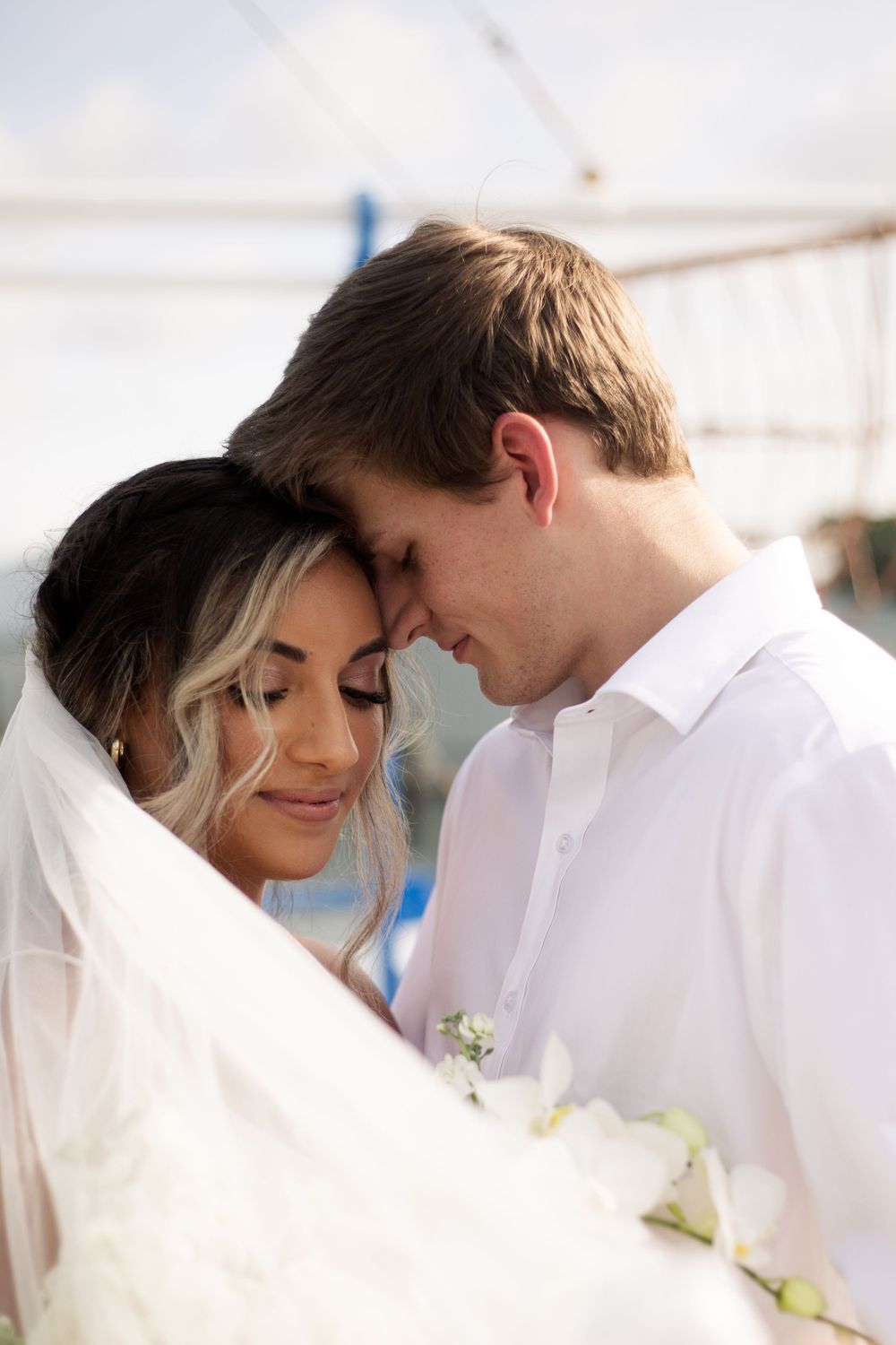 Intimate moment between newlyweds sharing a tender embrace by the waterfront.
