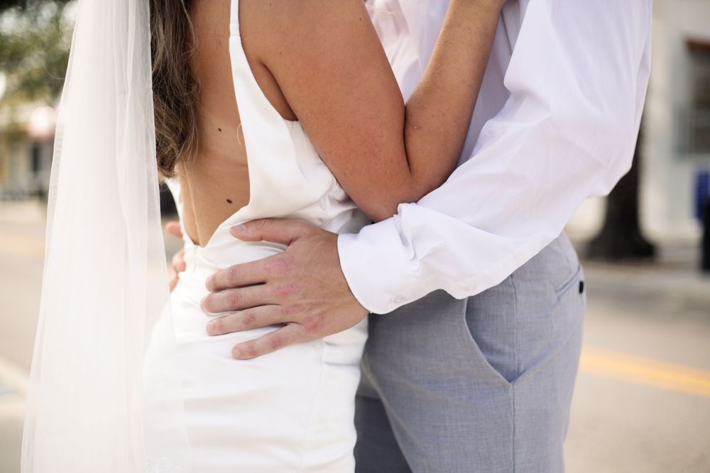Close-up detail of wedding couple embracing on a city street.