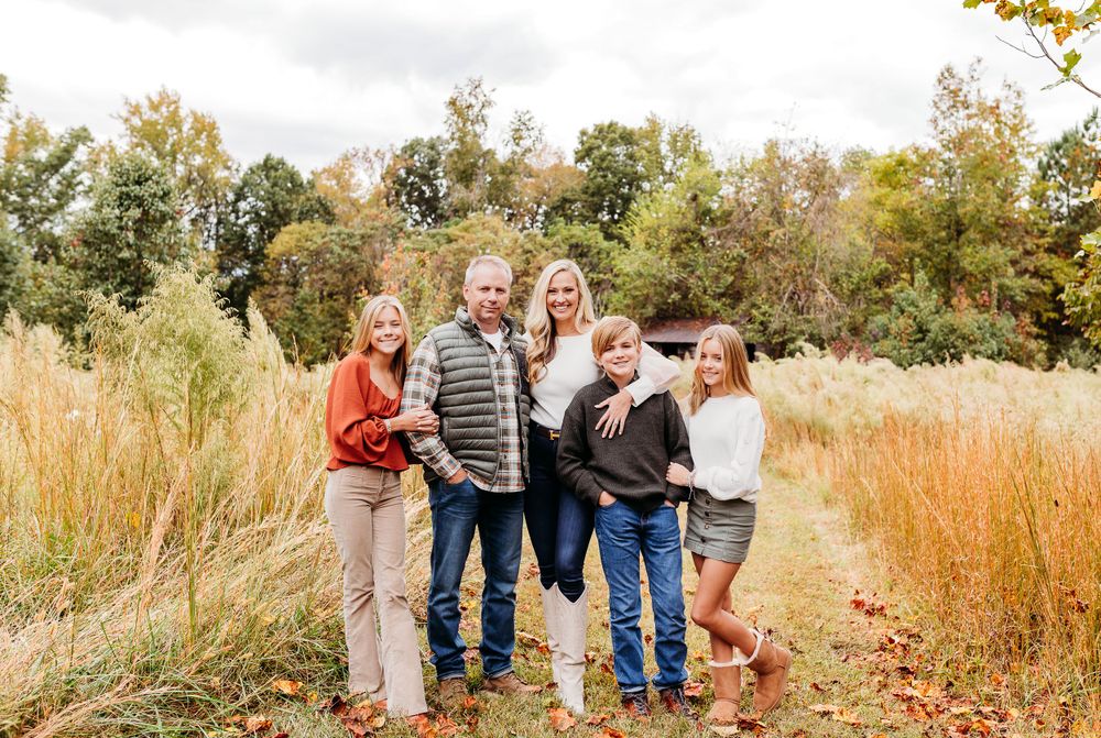 Family walking together through a golden autumn field during sunset photo session.