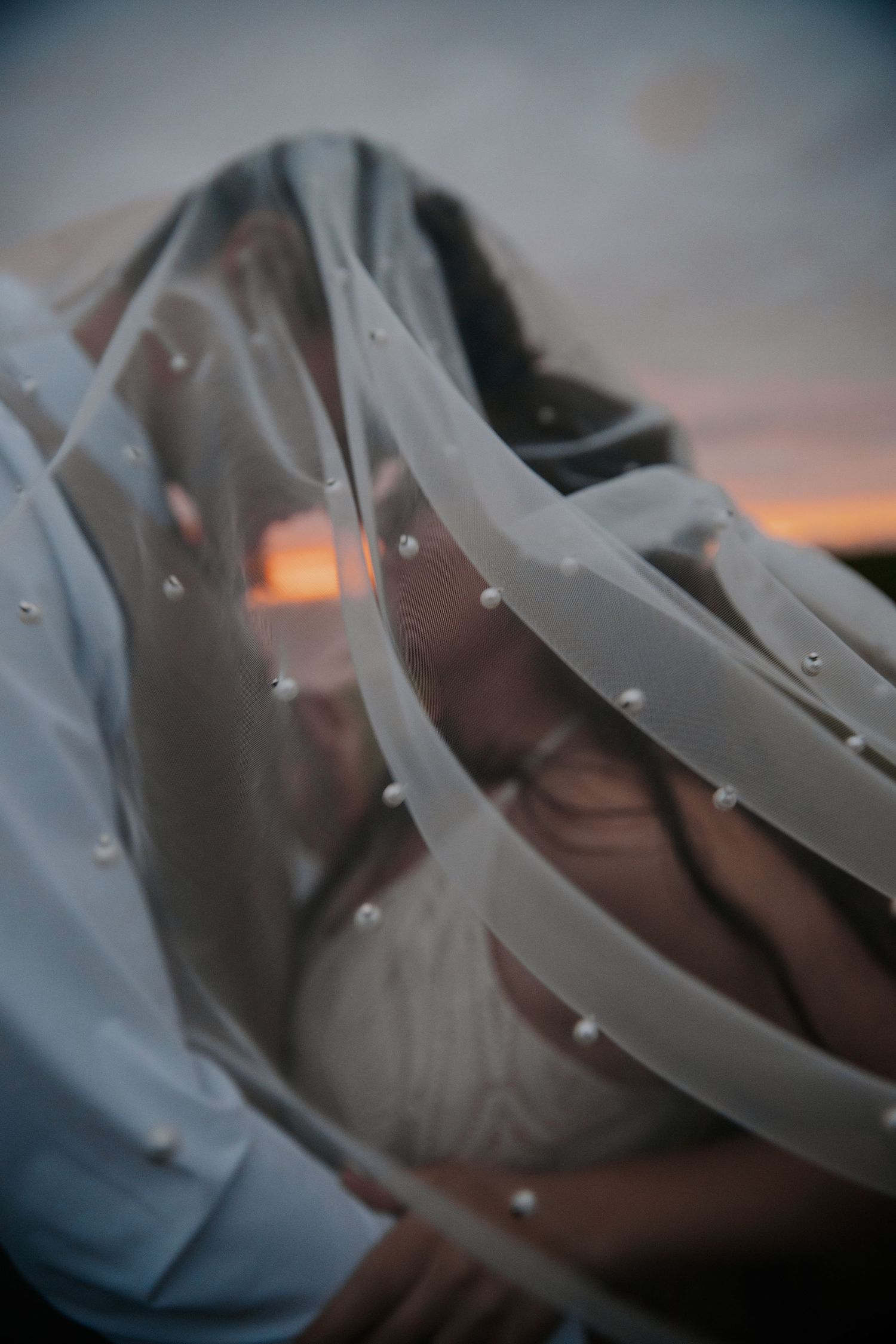 Abstract close-up details of a white veil flowing in soft lighting at sunset.