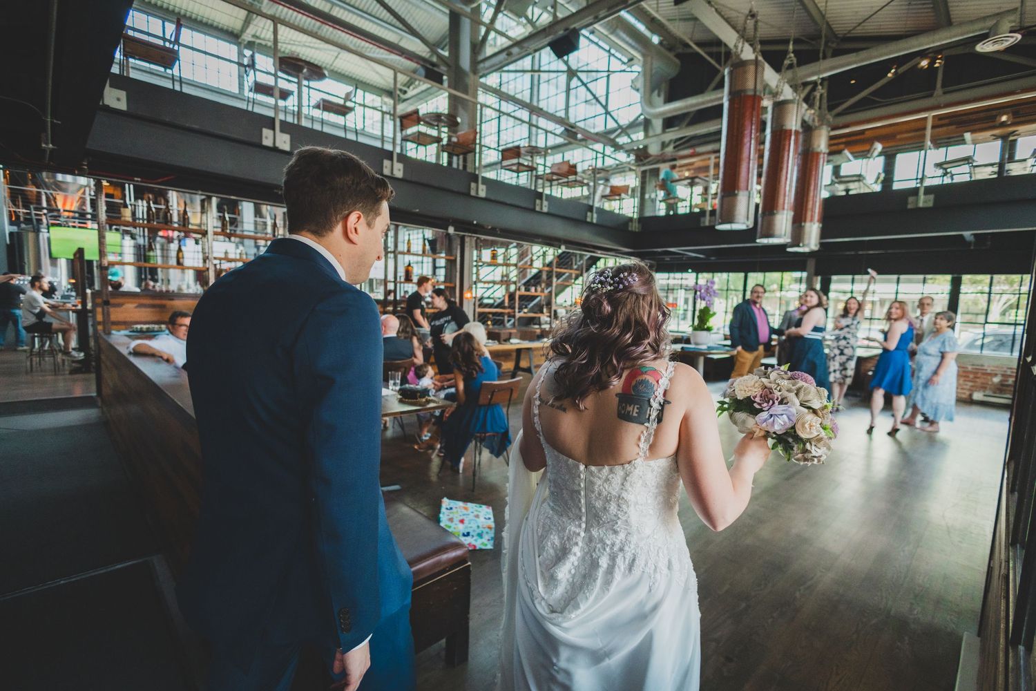 Wedding couple at reception venue with industrial-style interior and high ceilings.