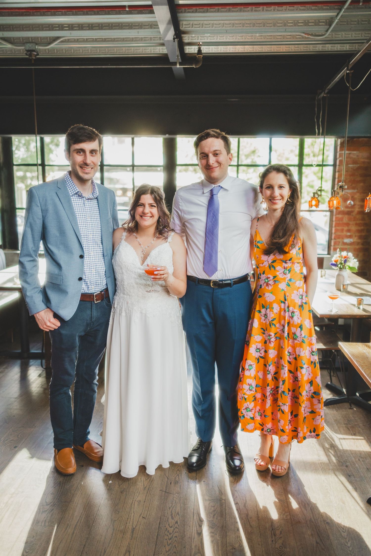 Wedding group photo in a modern industrial space with natural lighting.