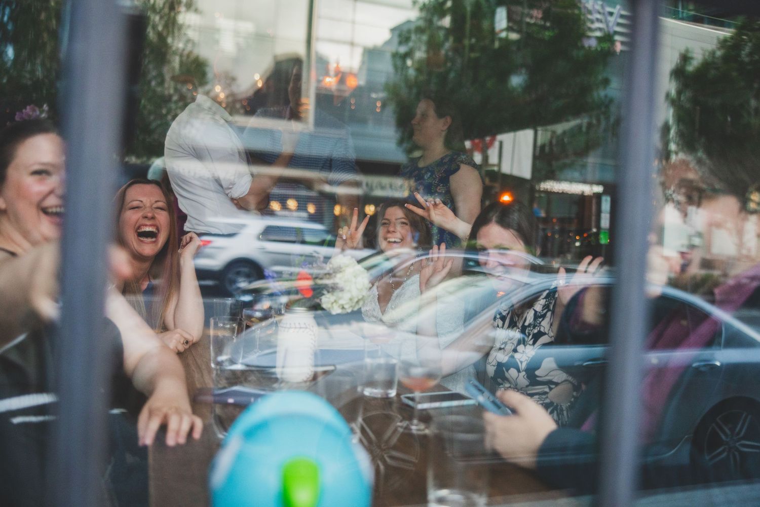 Wedding guests celebrating through window reflection at venue.