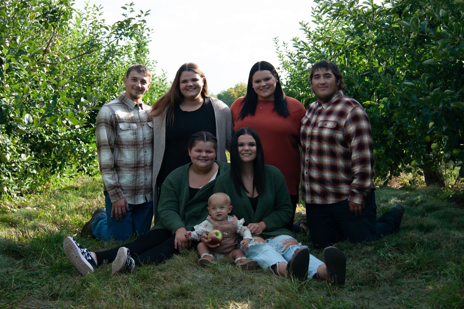 Family group photo in an apple orchard with casual fall attire.