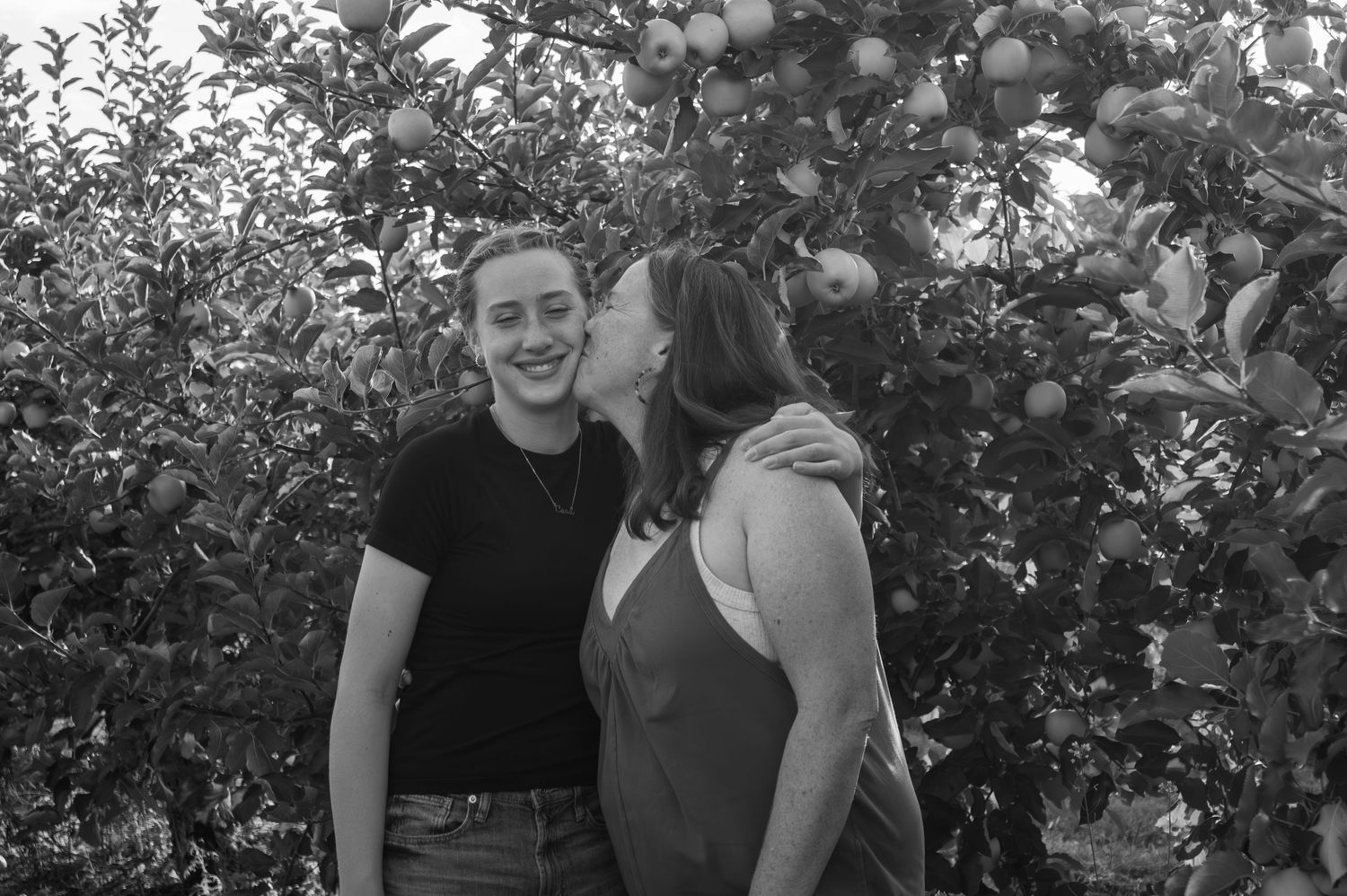 A black and white portrait of two people in an apple orchard.