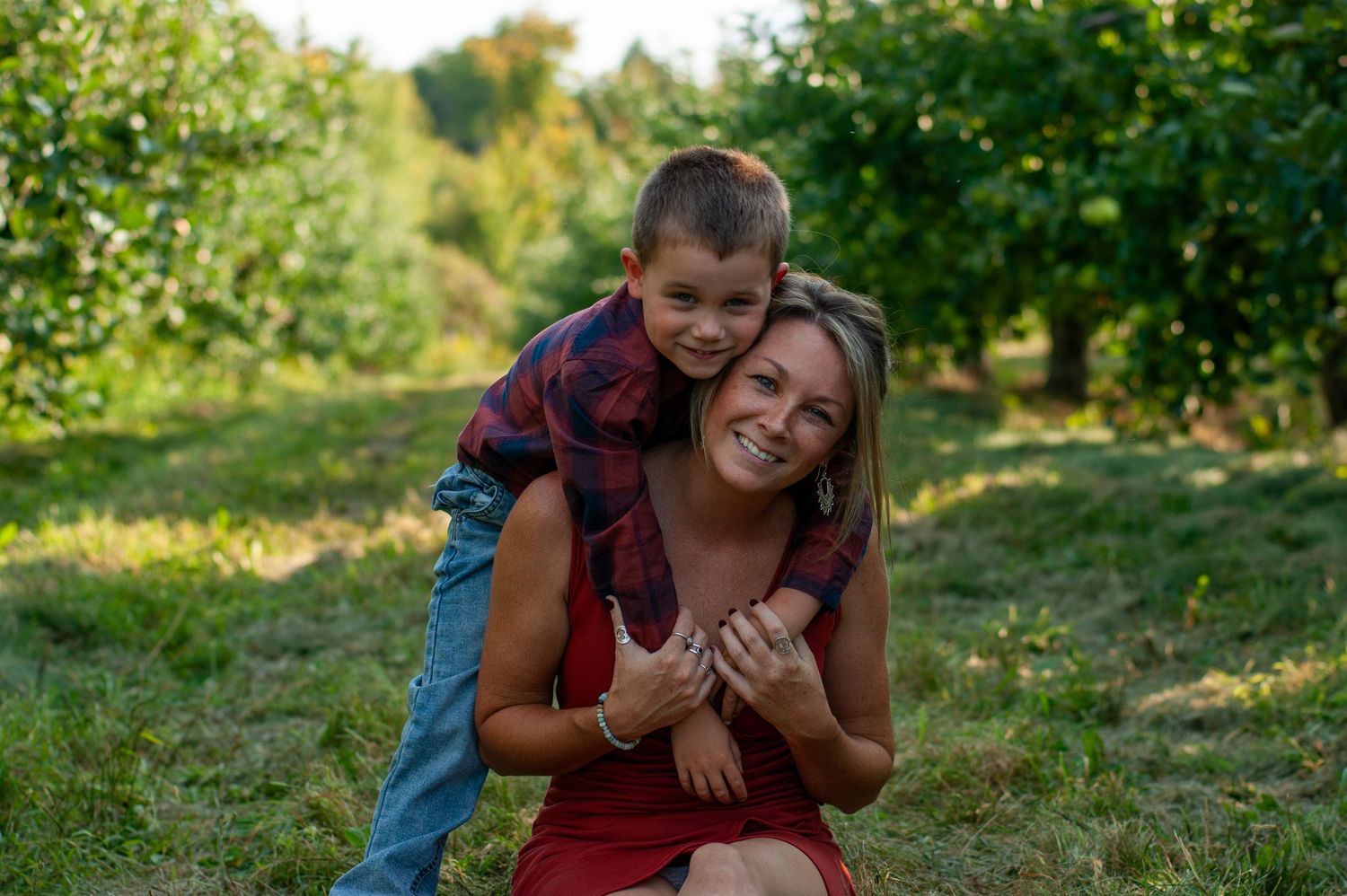 Joyful embrace between two people in a sunny apple orchard.