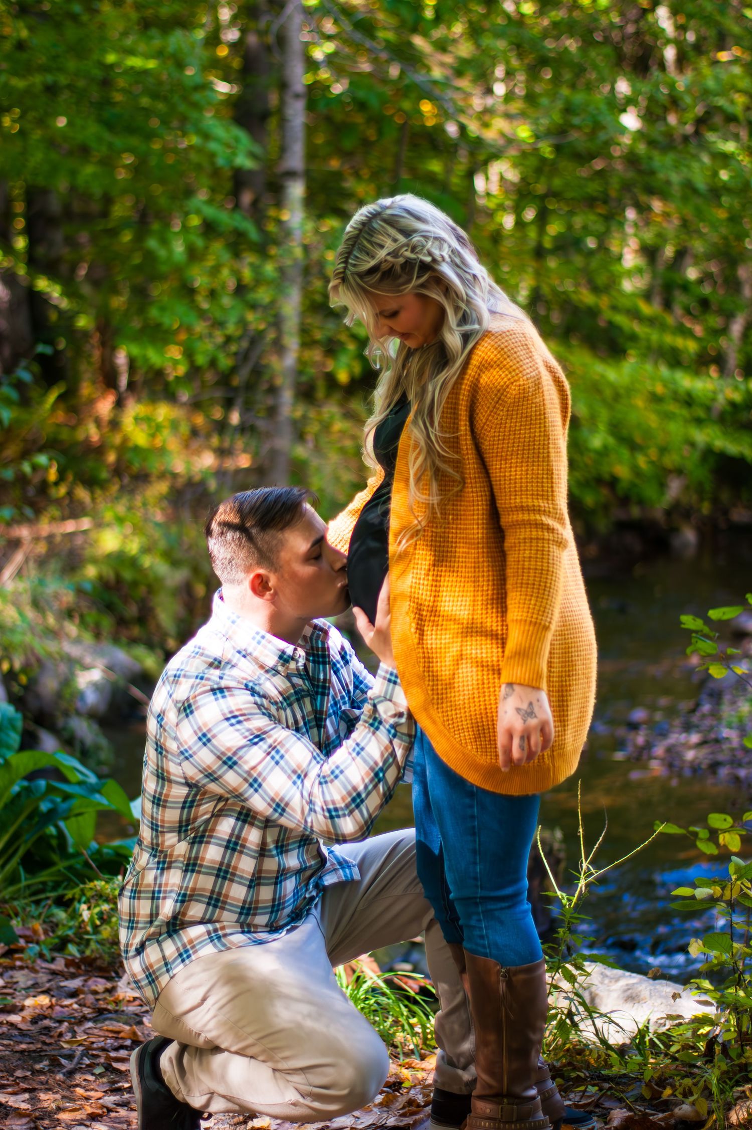 Sweet pregnancy announcement moment captured in fall woodland setting.