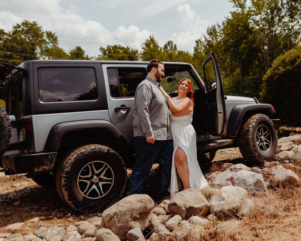 Romantic wedding photo featuring a lifted Jeep Wrangler on rocky terrain.