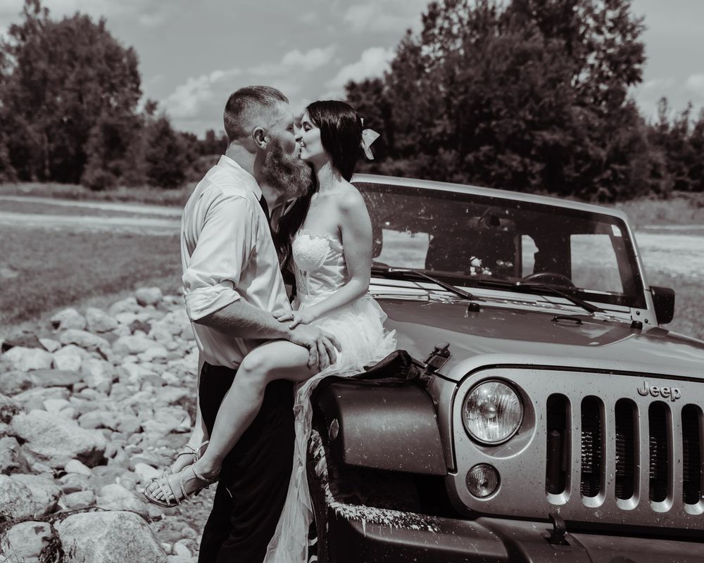Classic black and white wedding portrait with vintage Jeep.