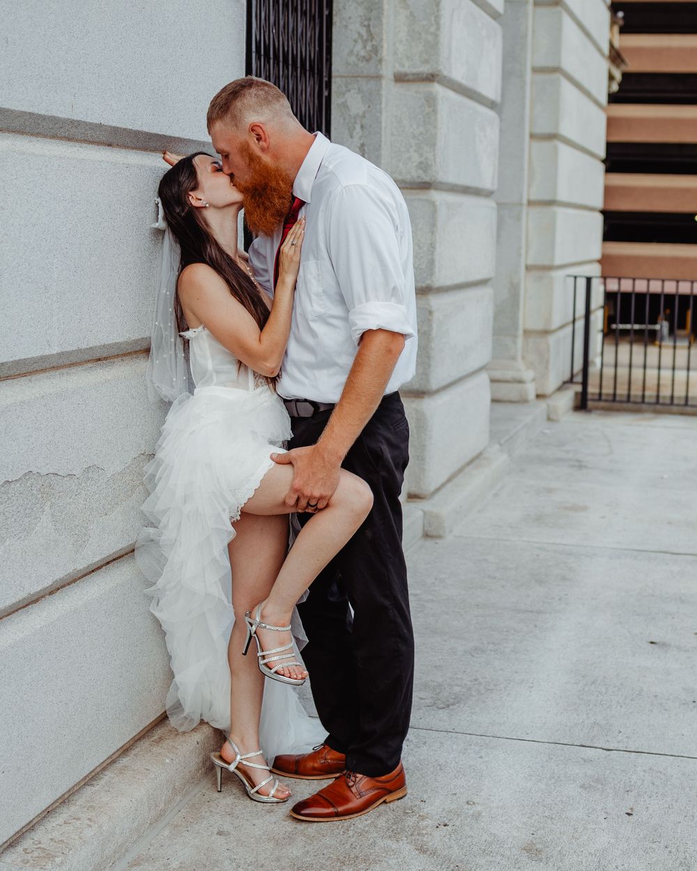 Intimate wedding moment photographed against classic architectural building details.