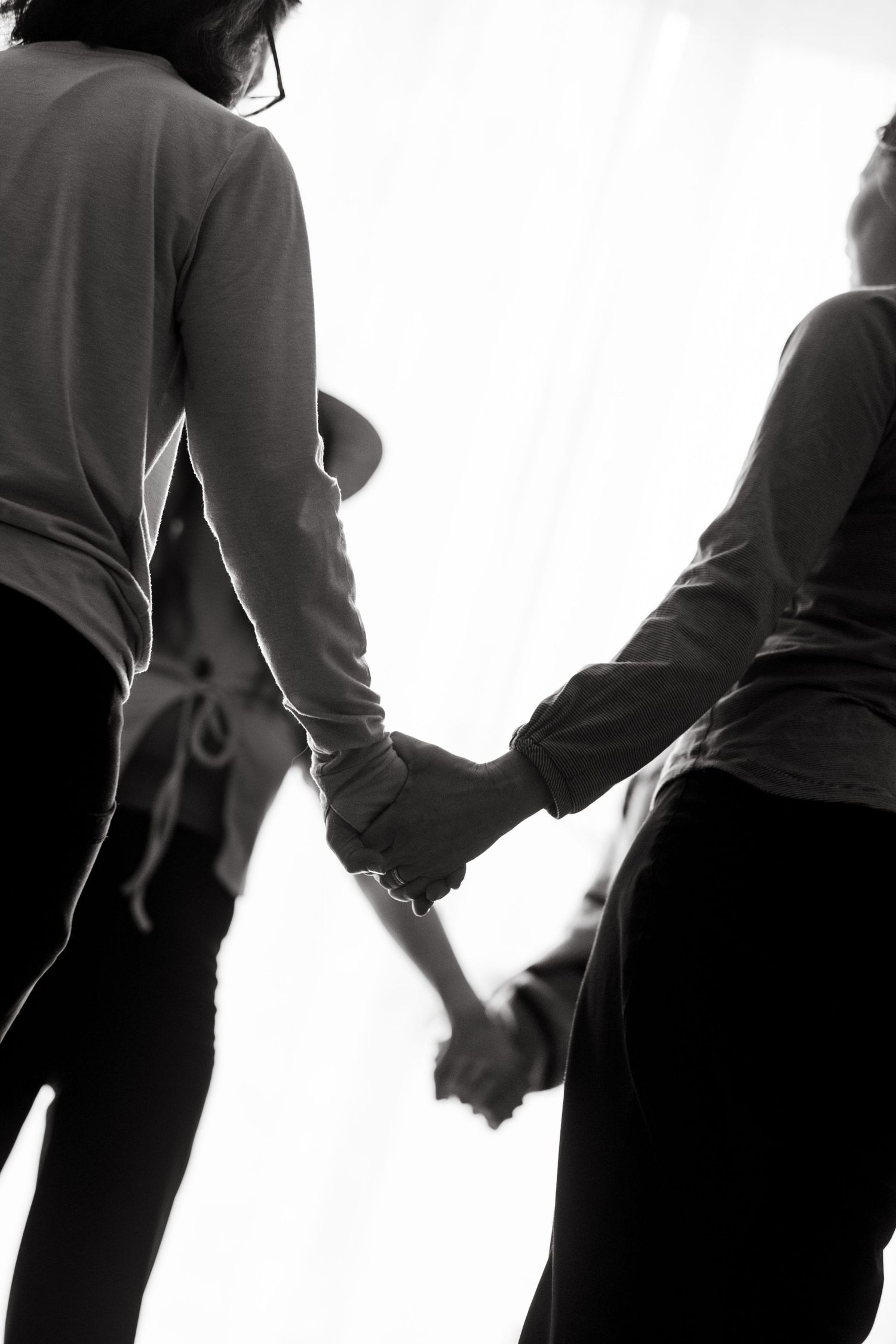 women standing in a circle holding hands in a yoga studio while being captured by retreat photographer