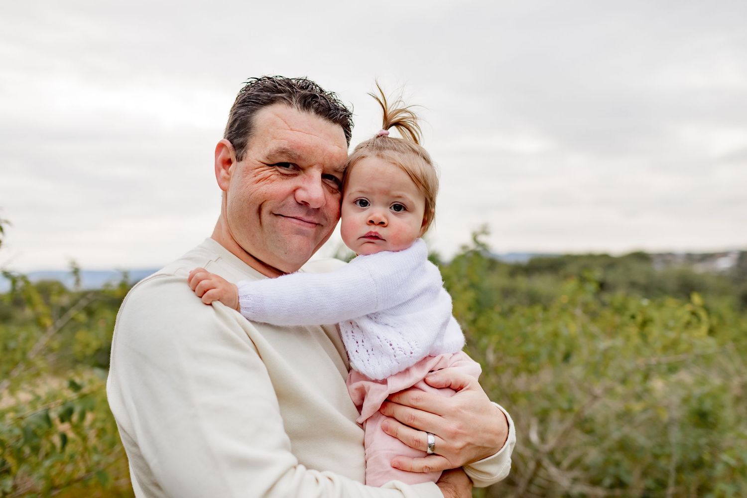 Sweet candid moment of parent and baby embracing in outdoor natural setting.
