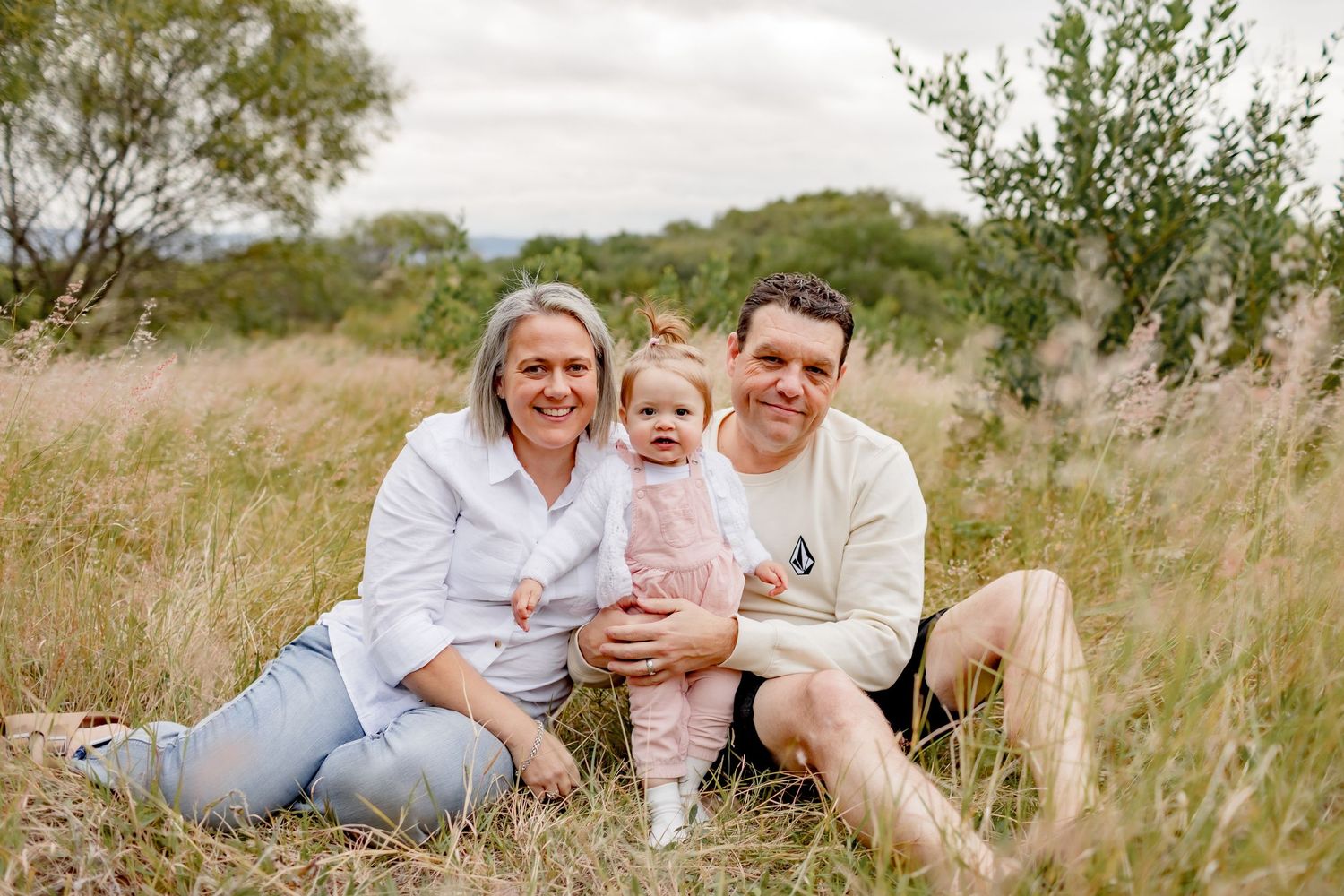 Natural family photo session in field shows relaxed poses and genuine smiles.