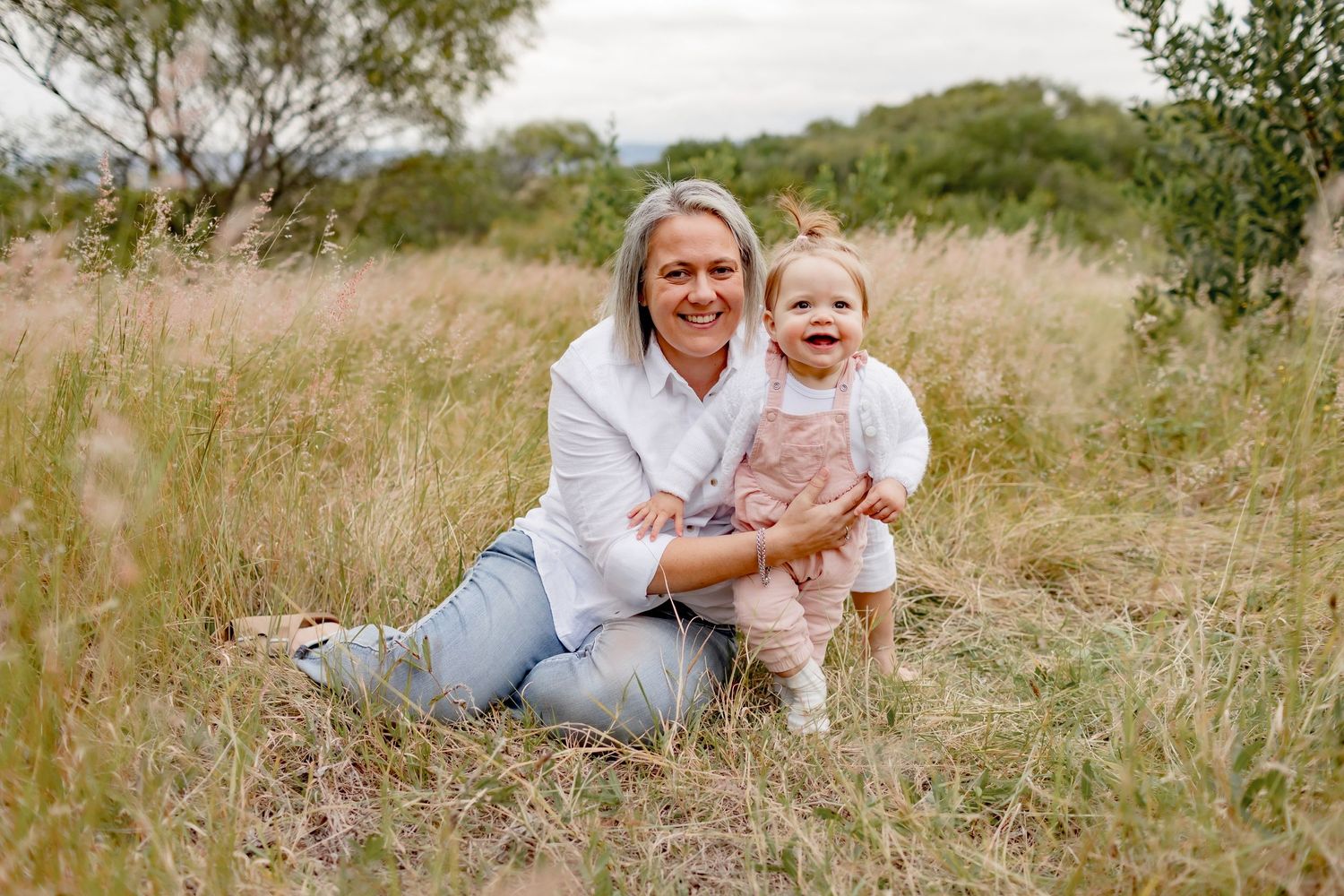 Parent and child outdoor portrait session in field of tall grass on overcast day.