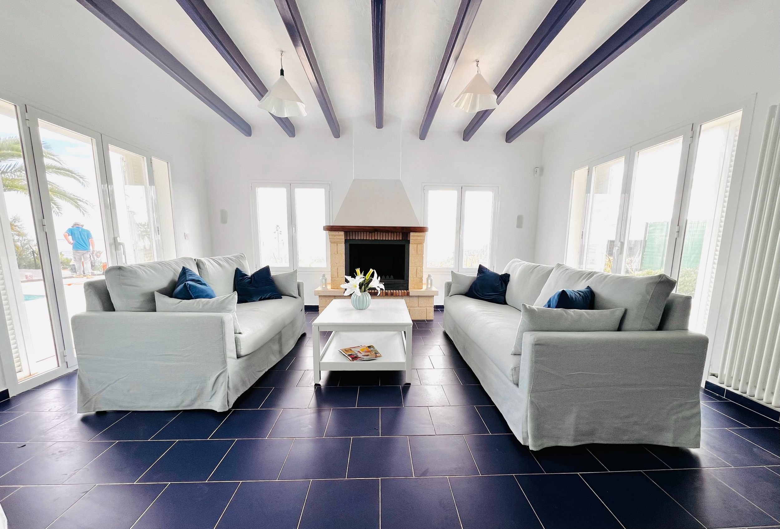Modern white living room with dark hardwood floors and large windows creating a bright, airy atmosphere.