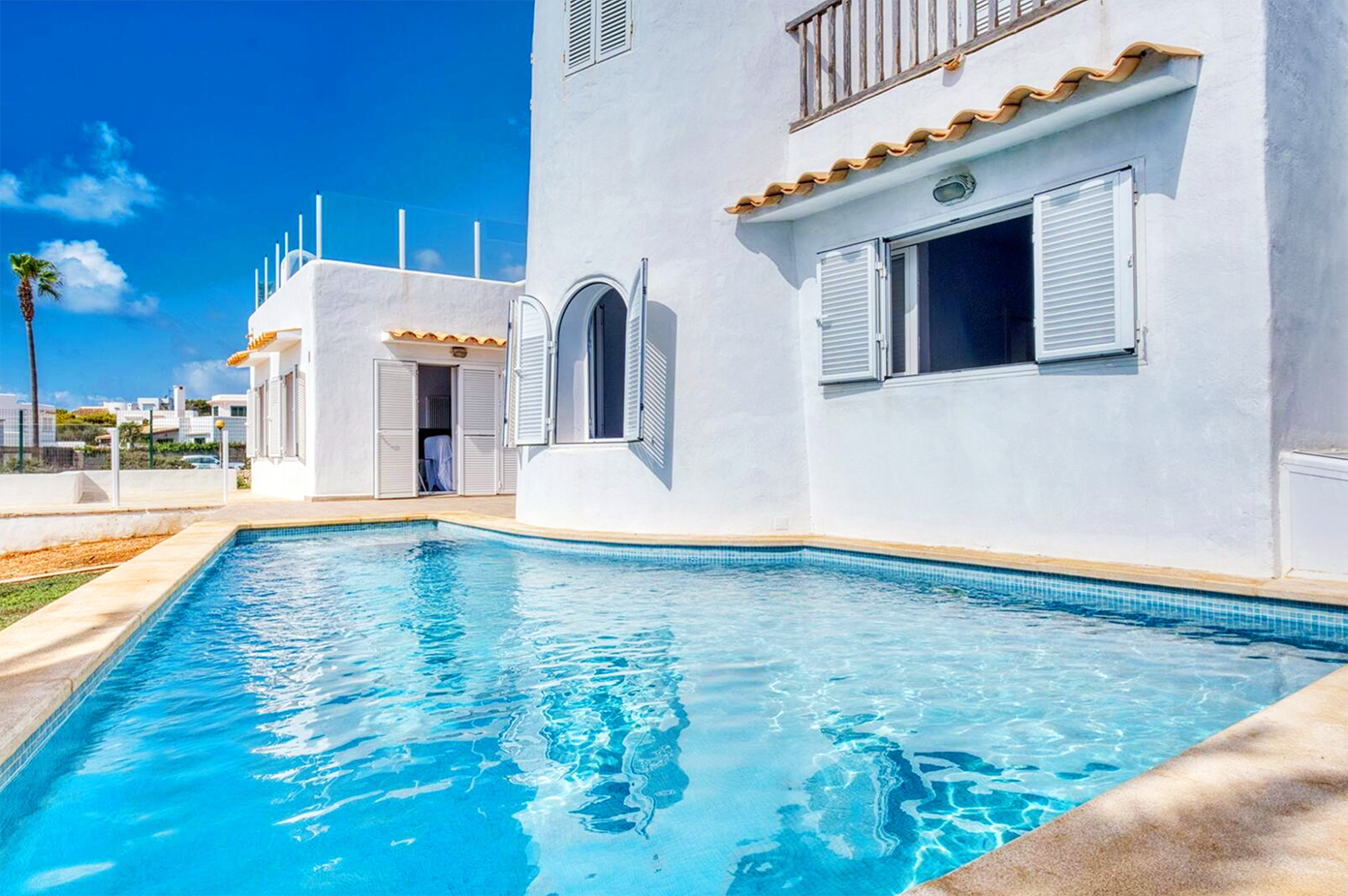 White Mediterranean villa with azure swimming pool and arched architectural details.