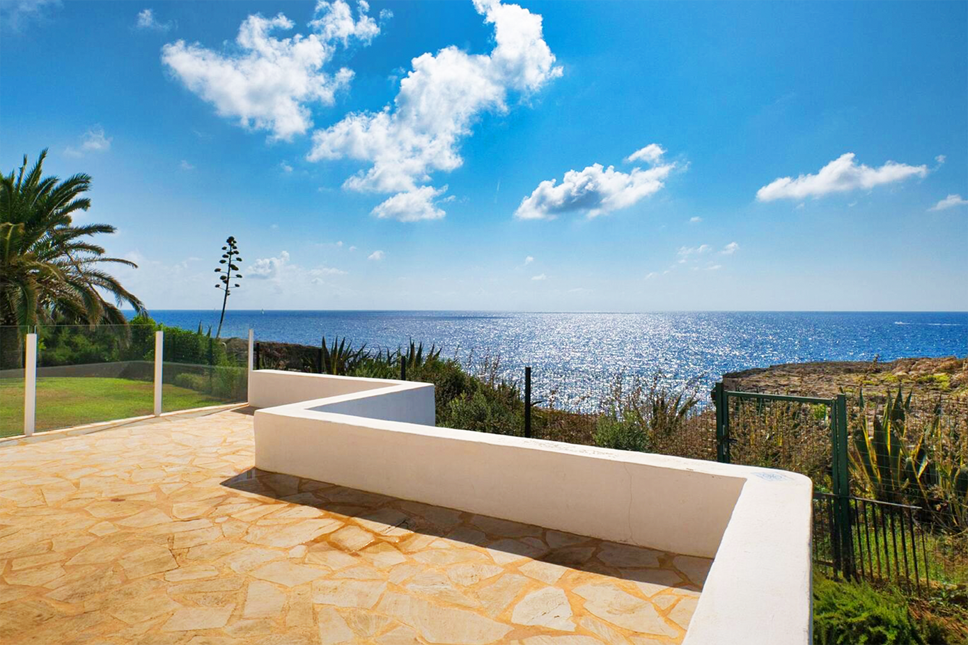 Oceanfront terrace with palm trees and Mediterranean Sea views on sunny day.