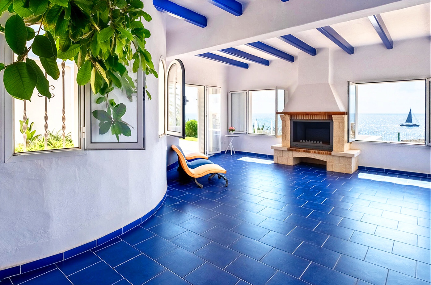 Spacious living room with blue tile floors, coastal views, and a white fireplace.