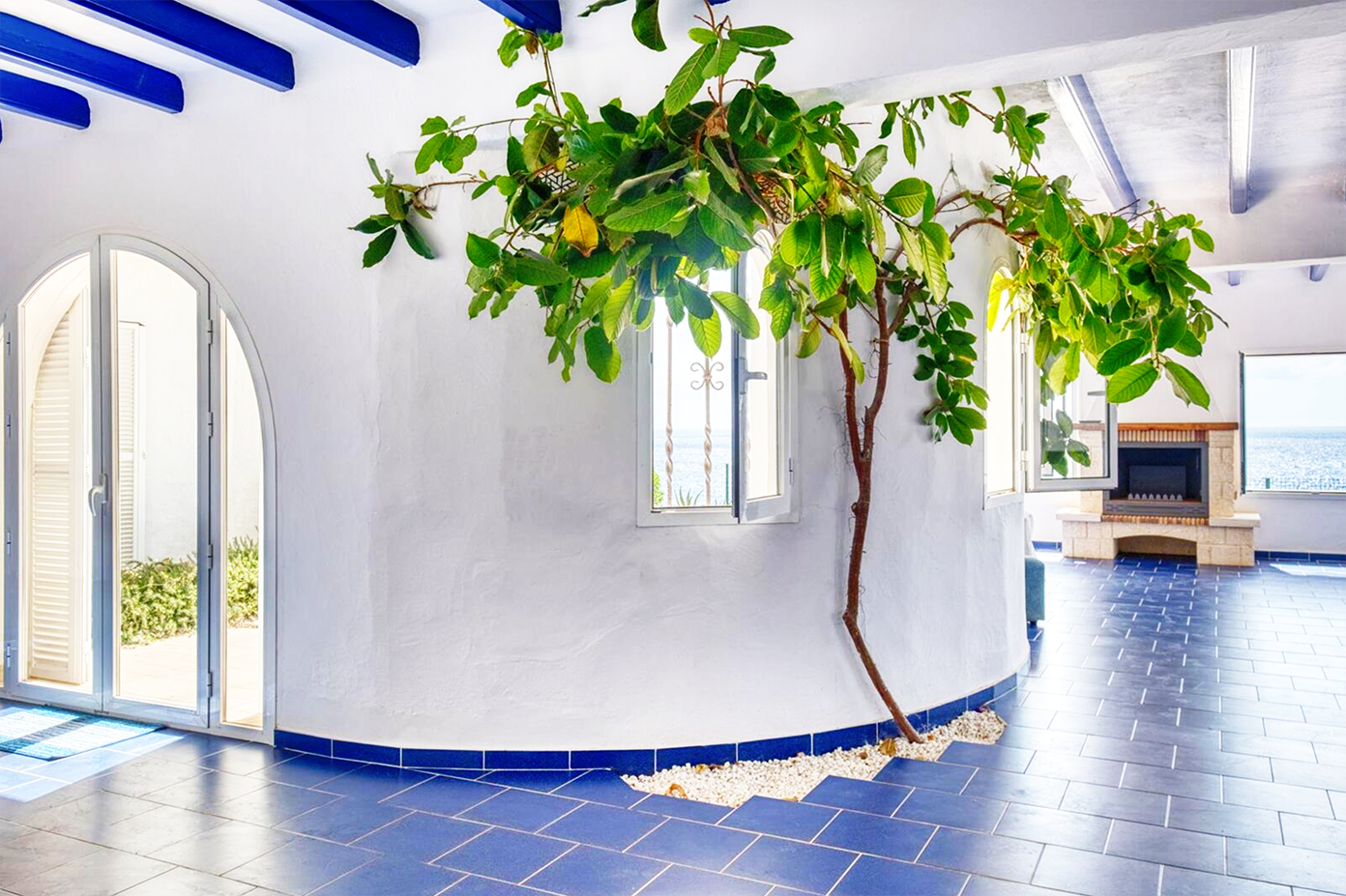 Mediterranean interior with blue-tiled floor, arched windows, and climbing indoor plants.