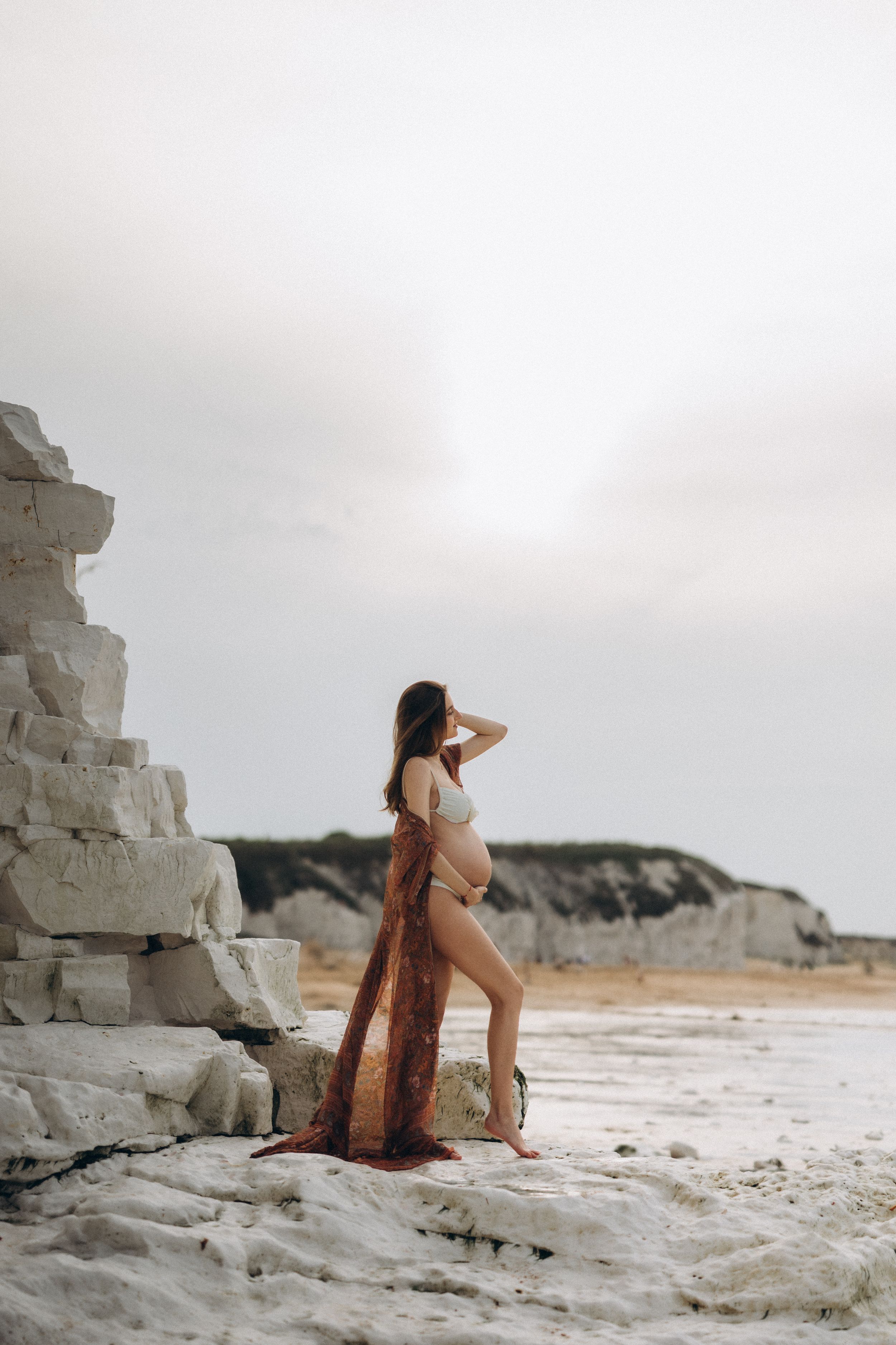 A pregnant woman standing on the beach