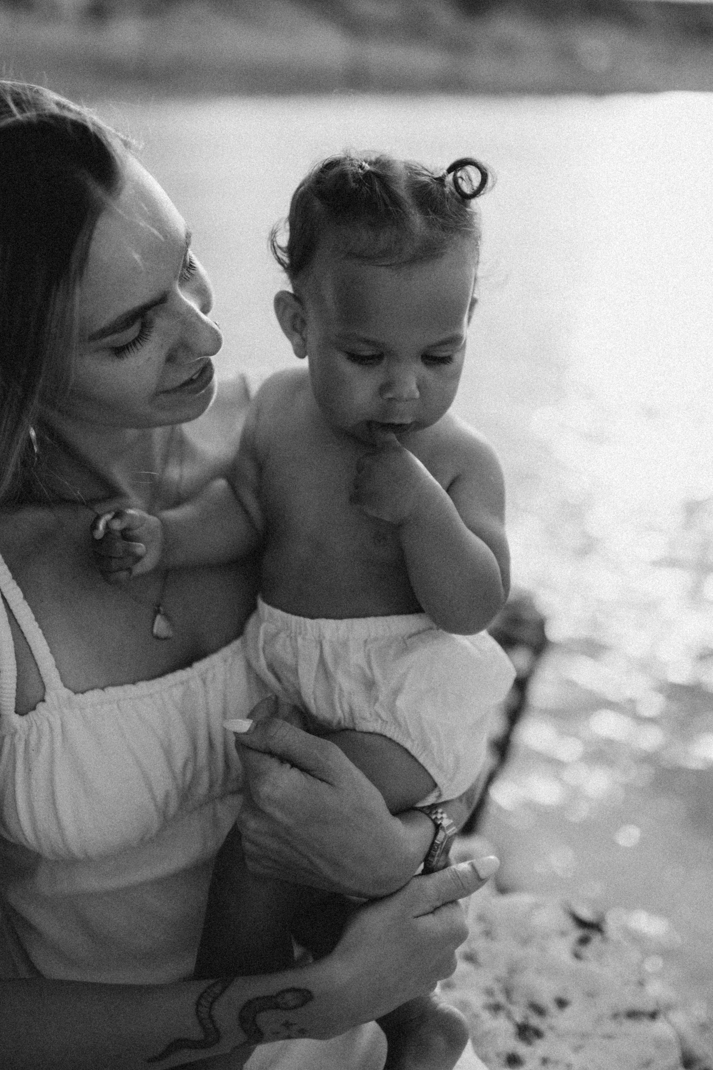 a mother holding her little girl and looking at her lovingly by the sea side during a motherhood photoshoot in Botany Bay, Kent