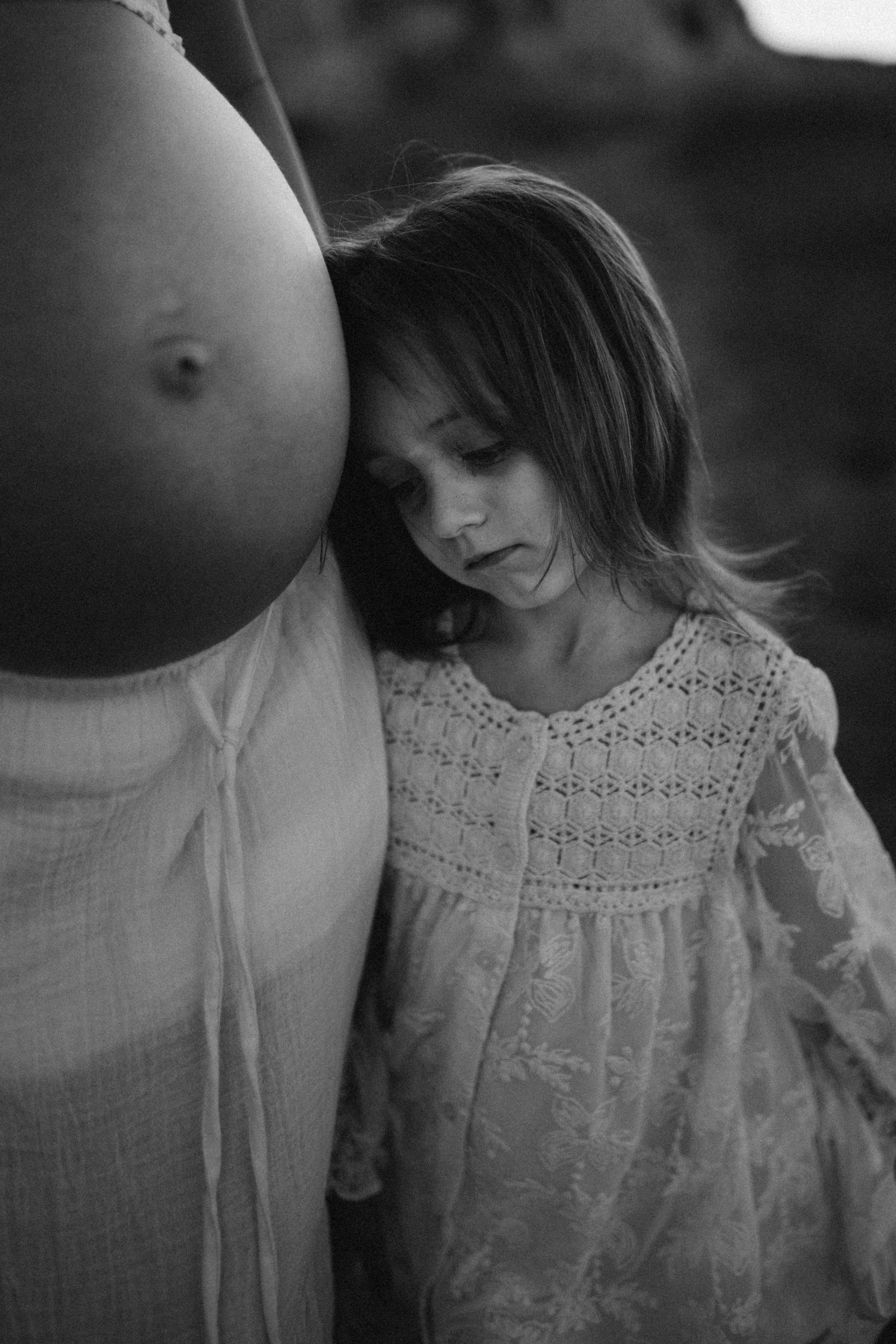 a little girl resting her head on her mom's pregnant belly